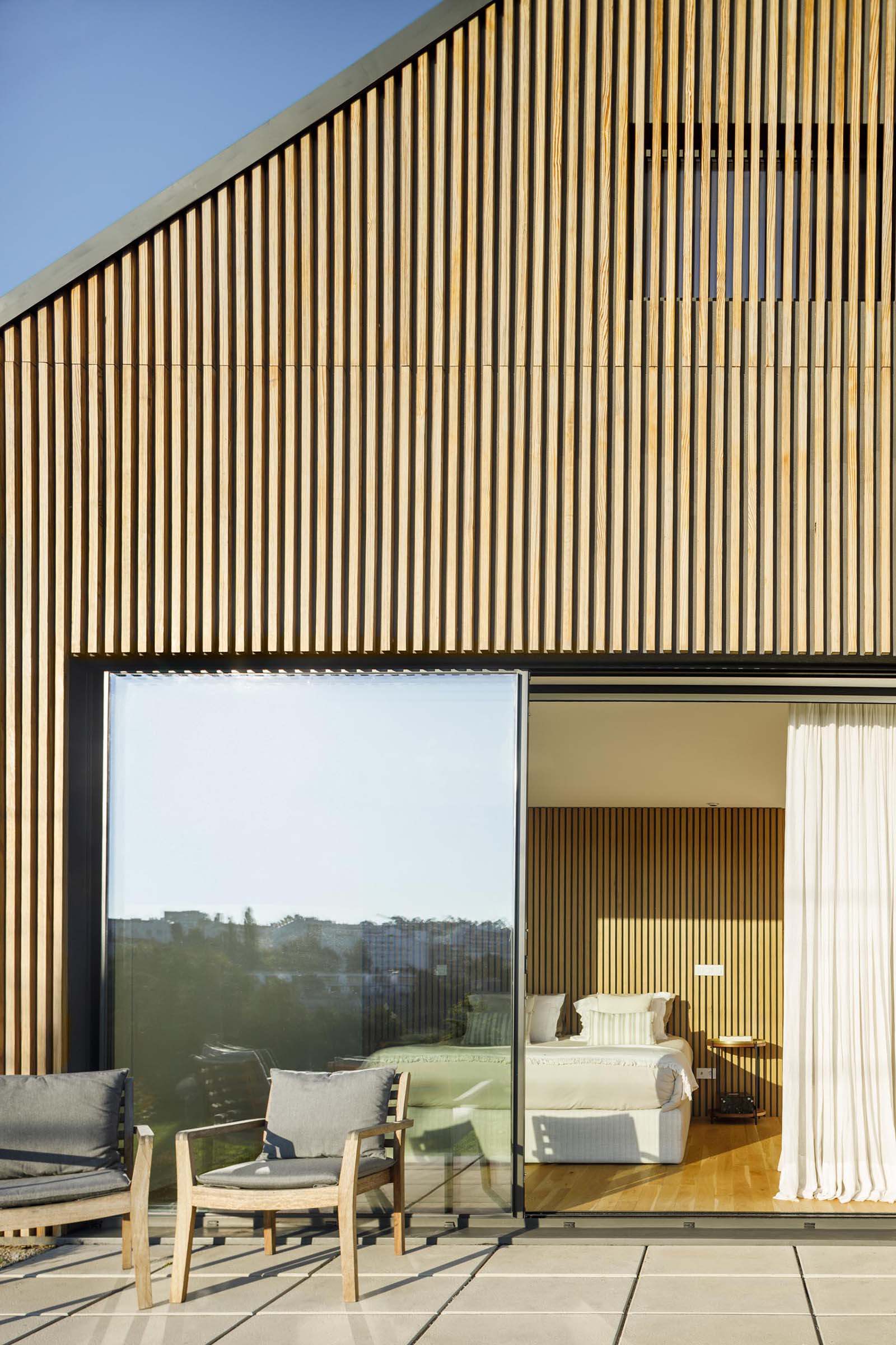 A modern house with a wood slat exterior and large sliding glass doors.