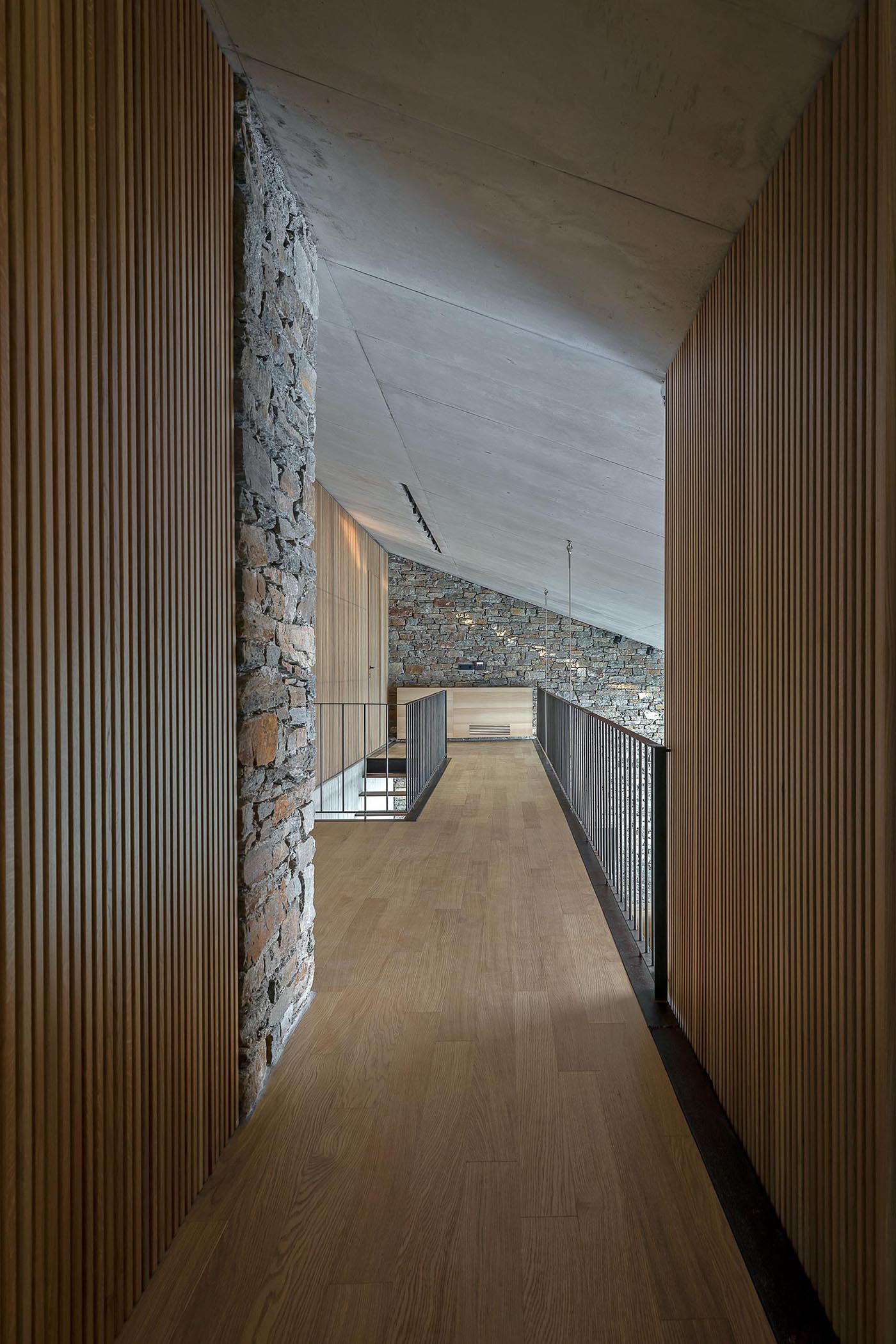 A modern home with stone walls and an interior bridge.