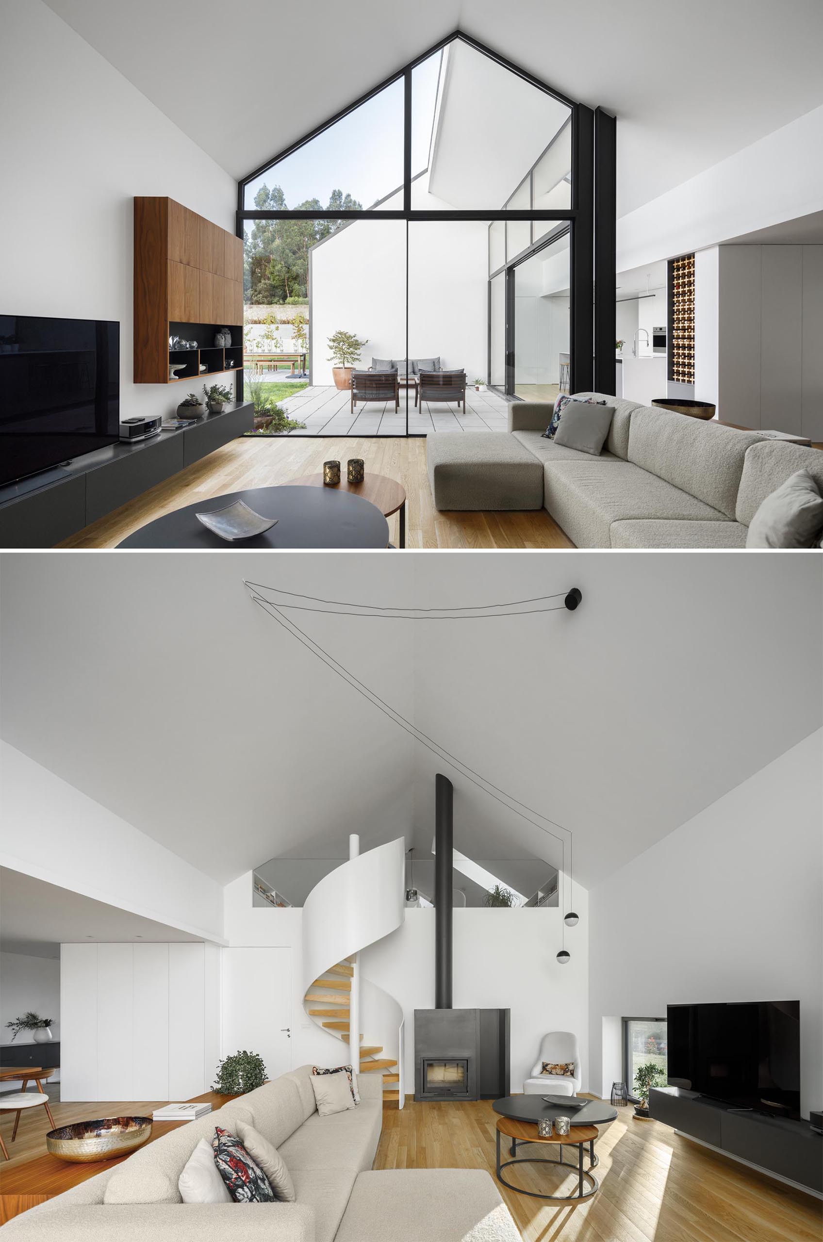 A modern living room with a gabled ceiling, white spiral staircase, and fireplace with a black steel surround.