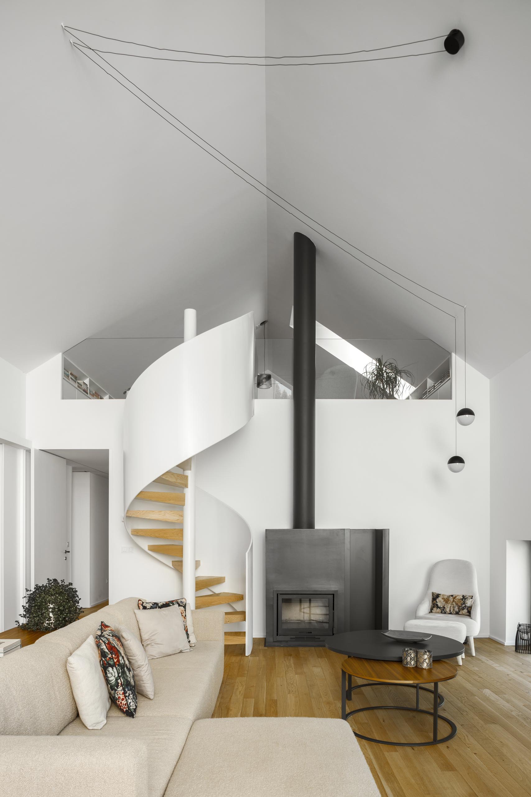 Modern white and wood spiral stairs and a fireplace with a black steel surround.