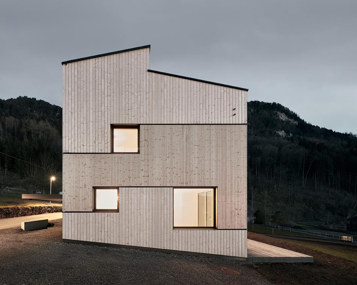 A modern wood house with different sizes of natural wood siding and black accents.