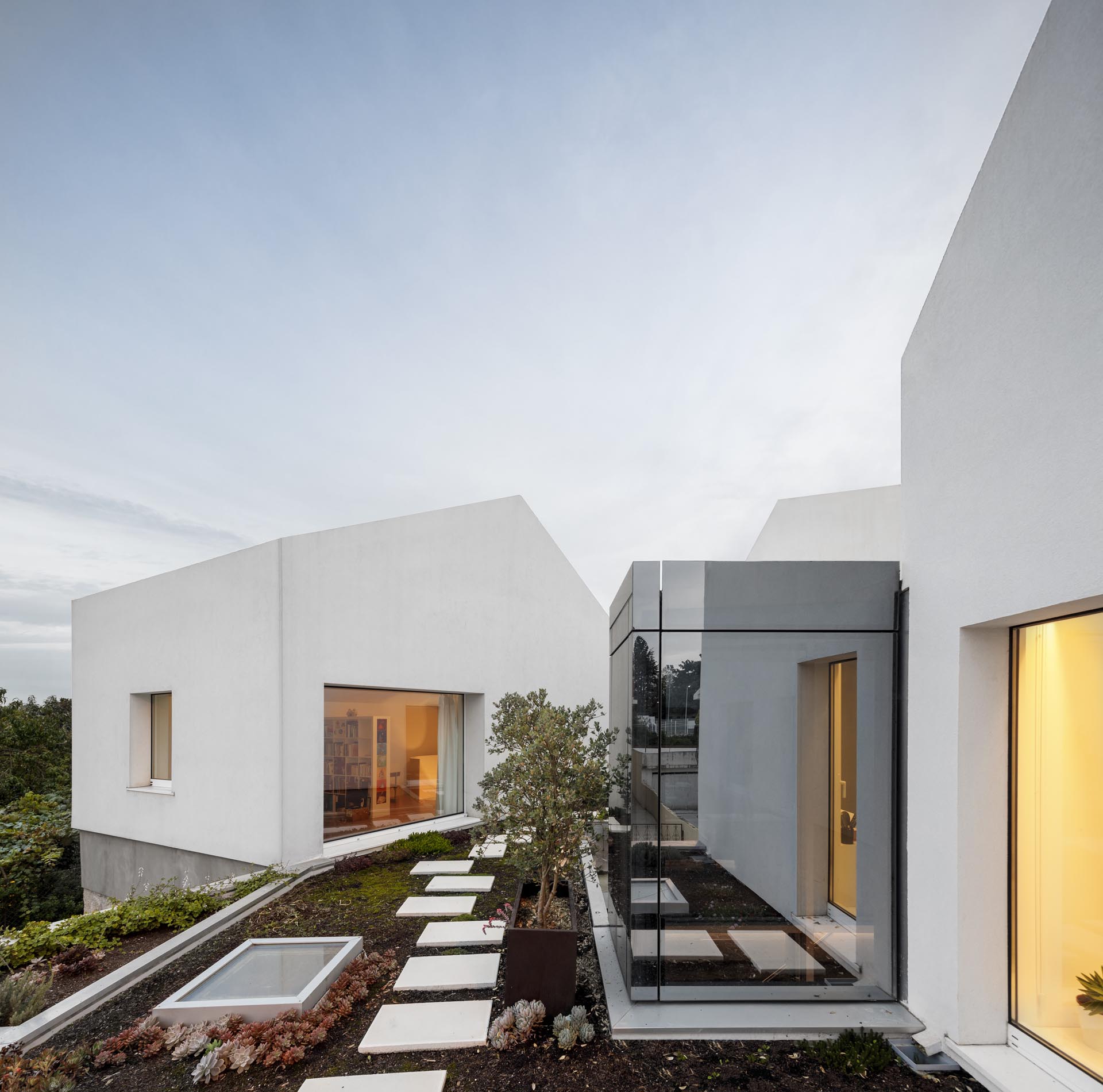 A modern home with stone walls, concrete and wood accents, and a rooftop garden.