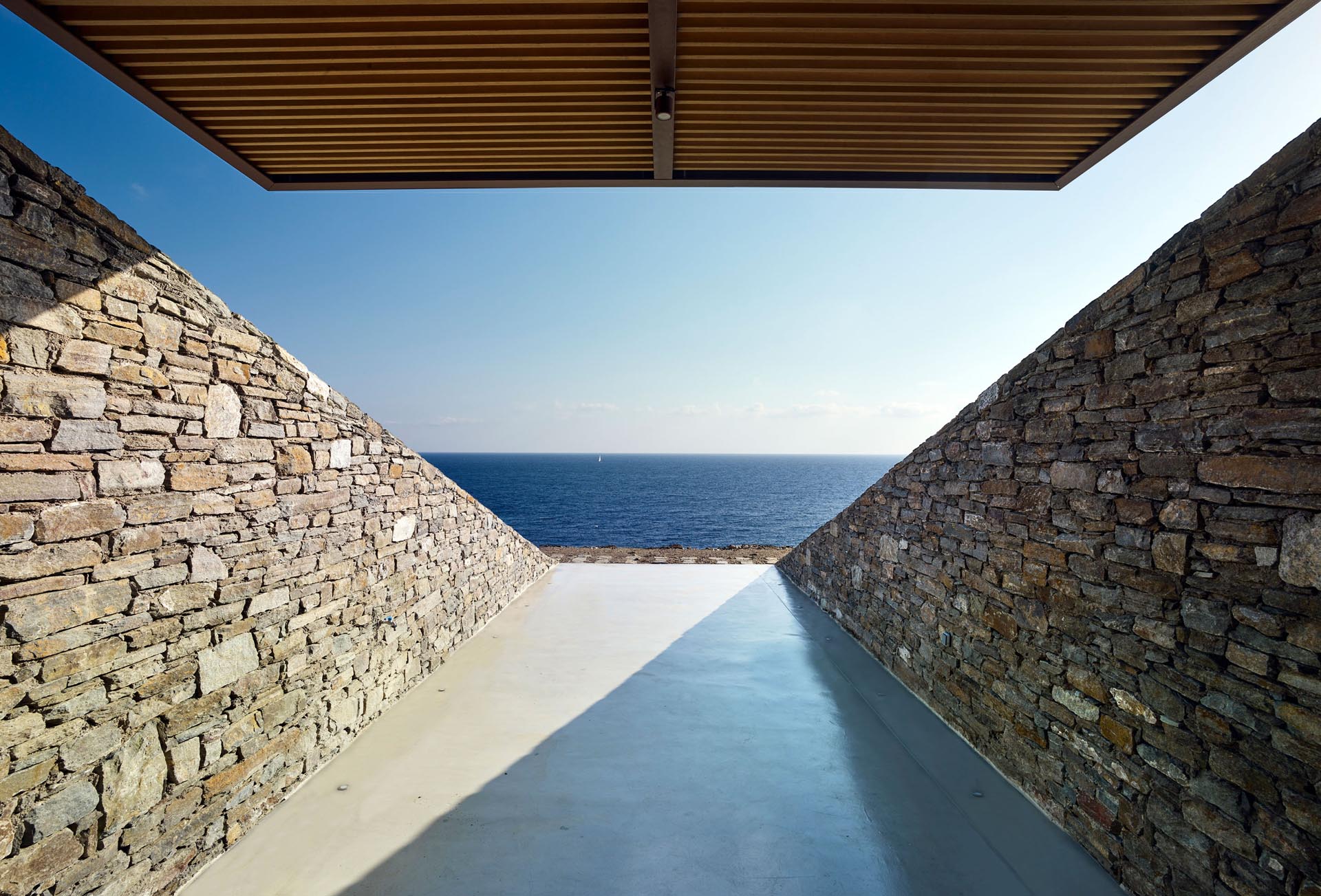 A modern home that's built into a hillside has stone walls.