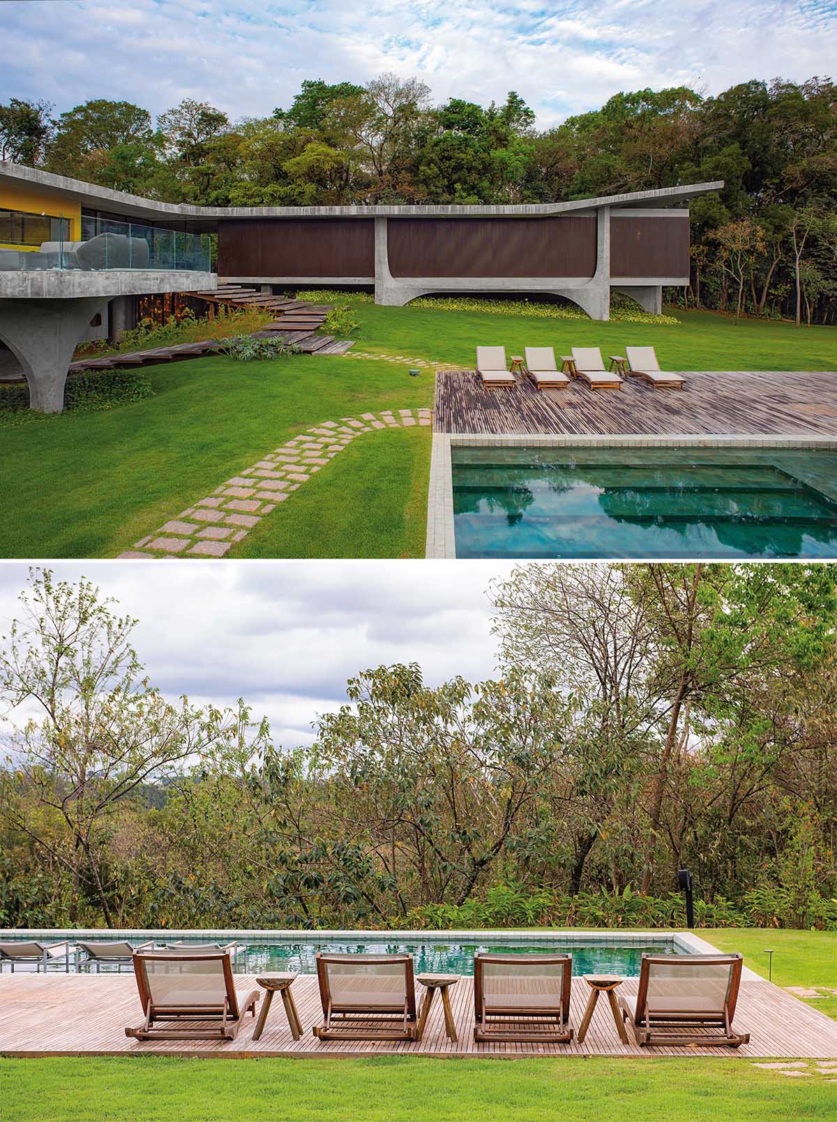 This modern concrete house has wood stairs that lead down to a swimming pool and deck.