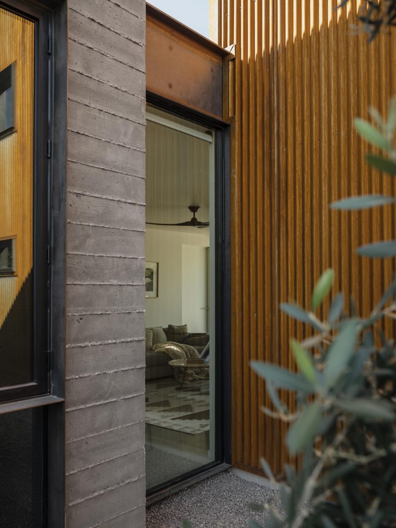 A modern home with board formed concrete walls, steel beams, and corrugated metal siding.