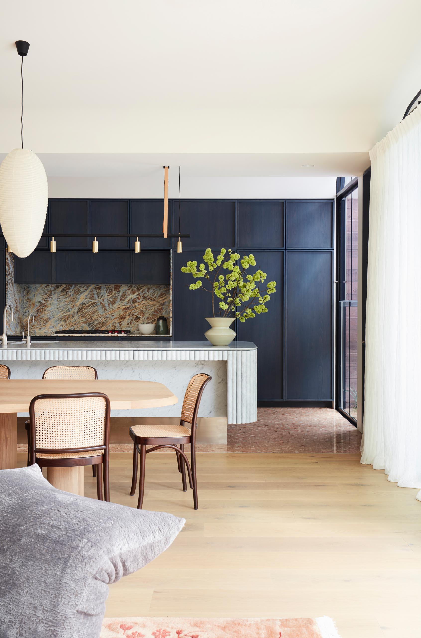 A modern kitchen with dark hardware free cabinets, and a curved island.