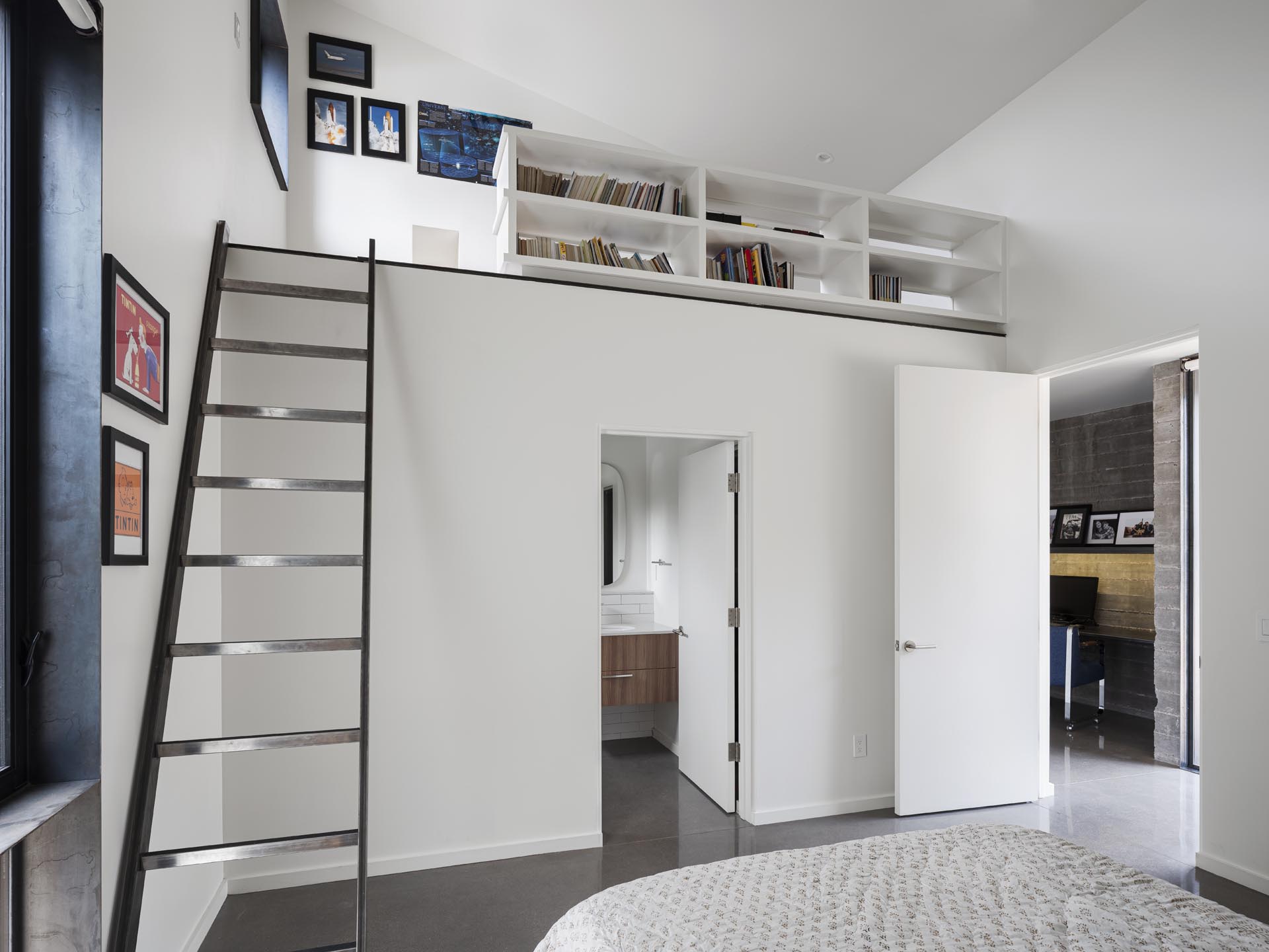 In this modern bedroom, there's a lofted reading area and an en-suite bathroom.