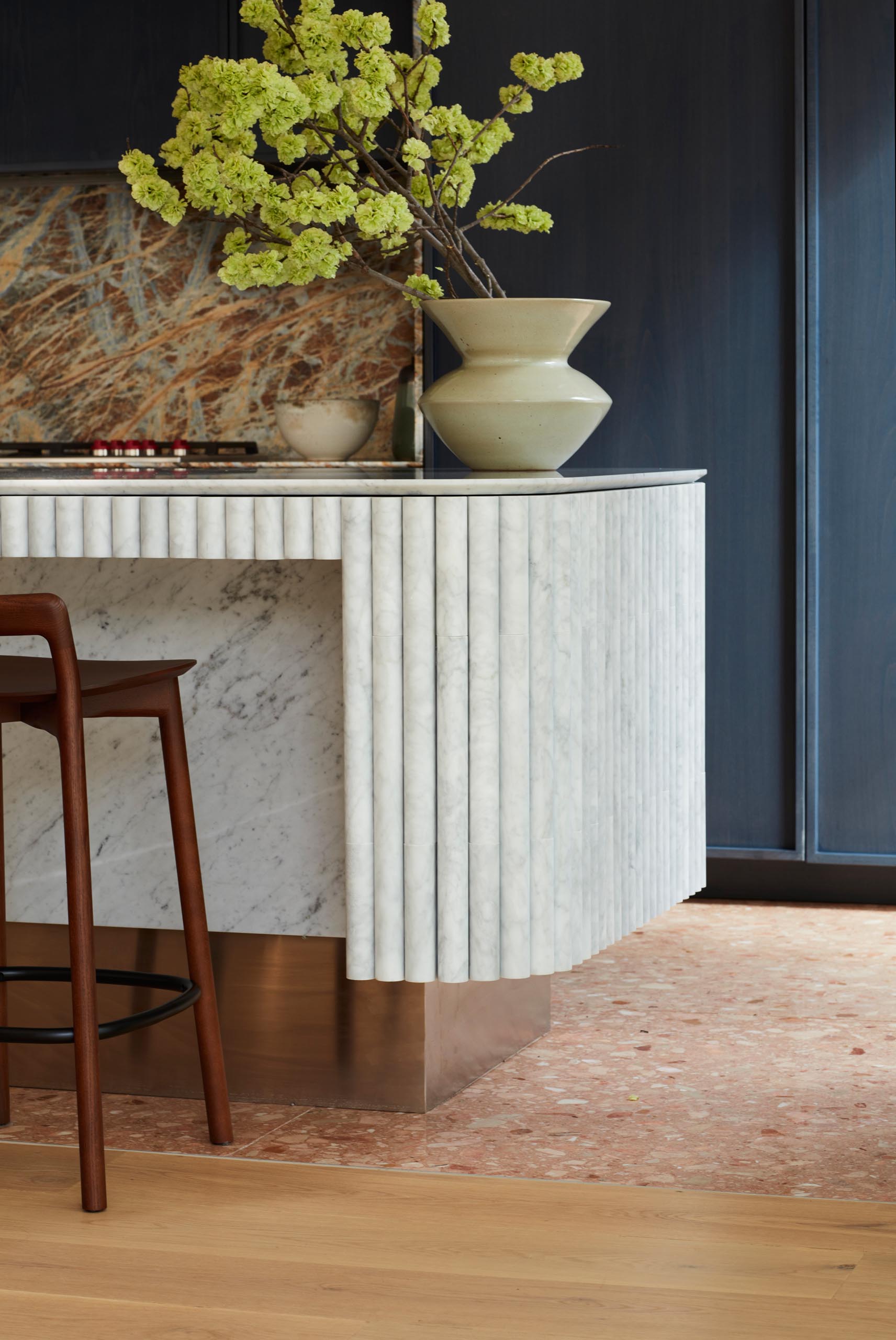 A modern kitchen with dark hardware free cabinets, and a curved island.