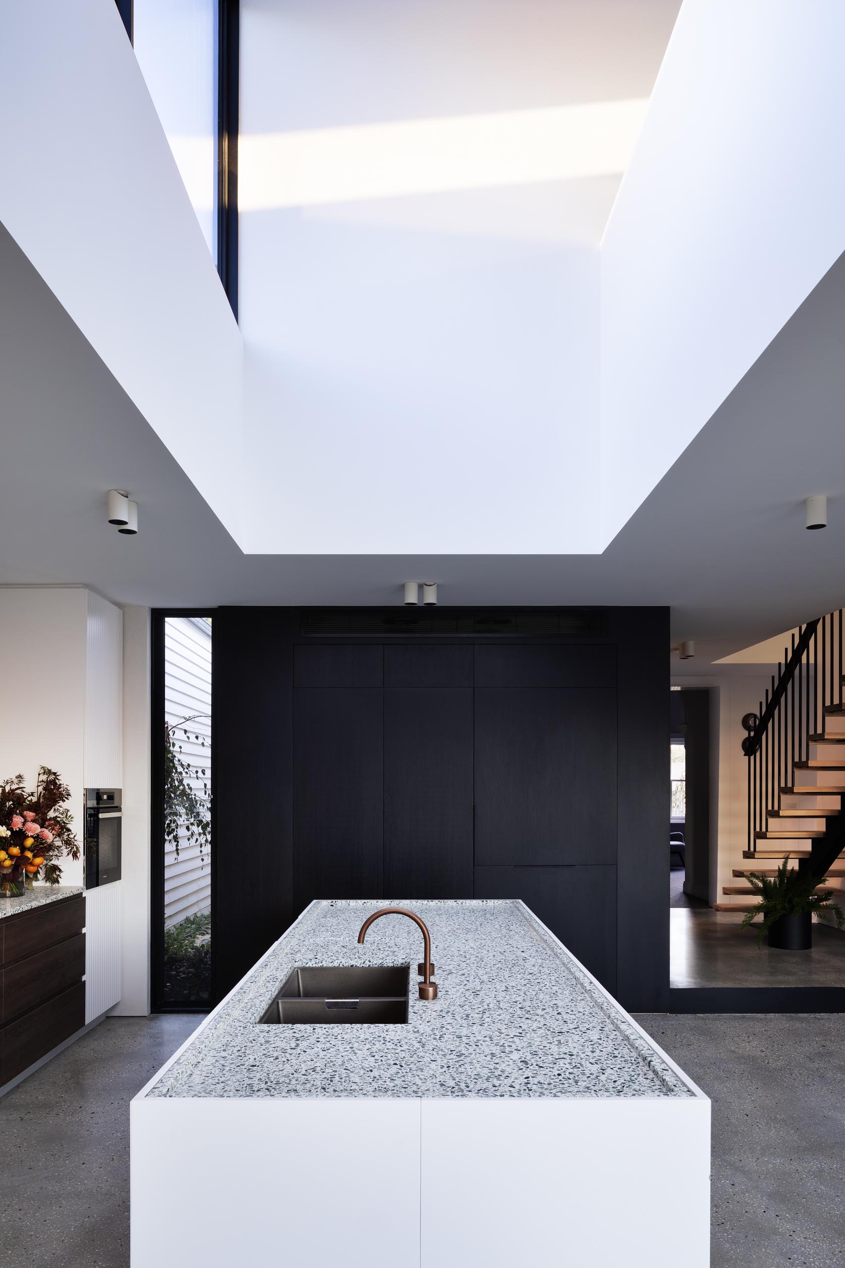 In this modern kitchen, dark wood cabinets line the wall in the kitchen, and the kitchen island features an inset countertop.