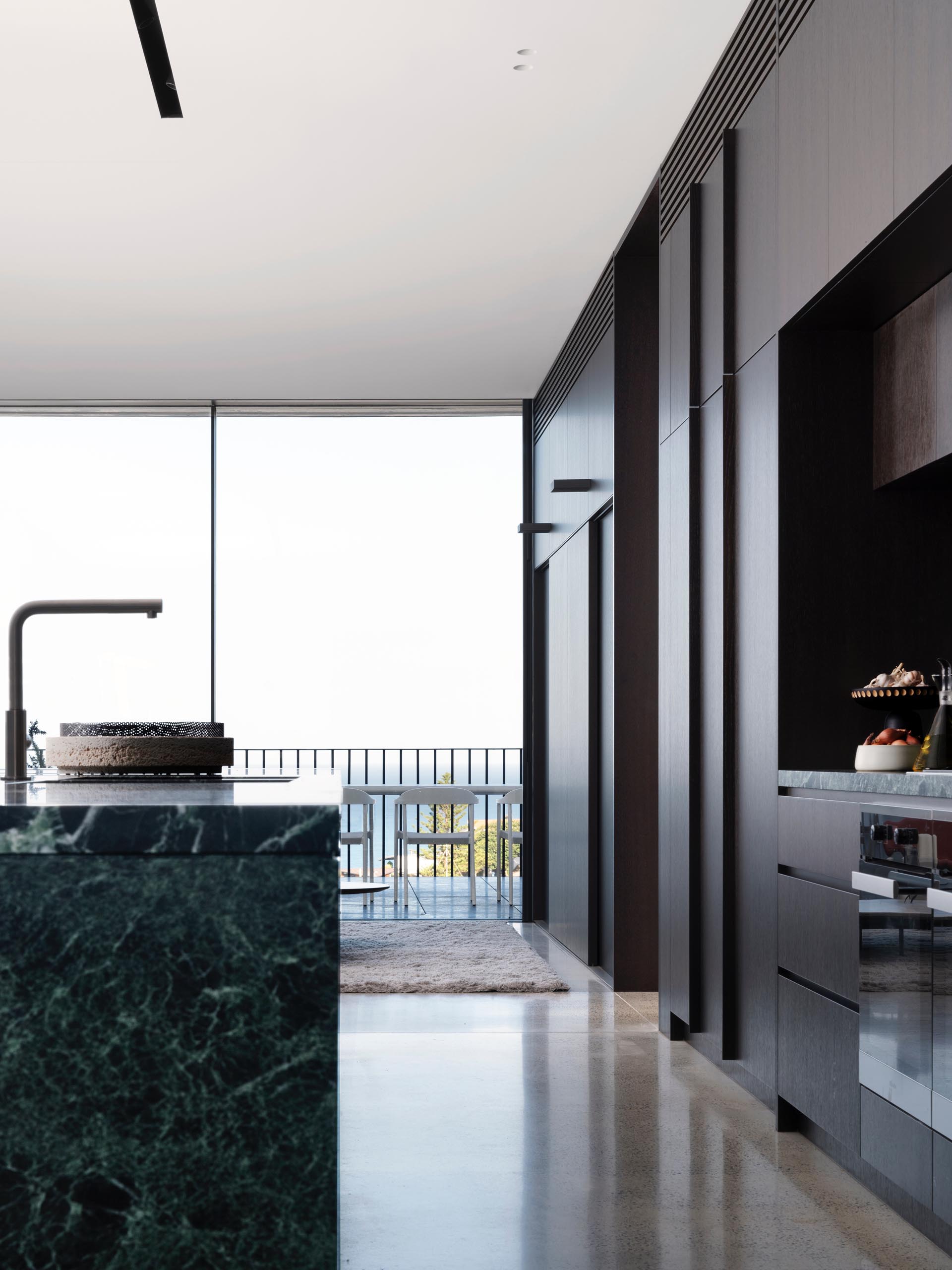 In this modern kitchen, dark wood cabinets complement the gray/black feature marble used on the island and backsplash.