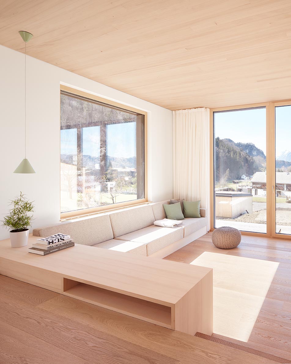 A modern living room with a built-in sofa and large windows.