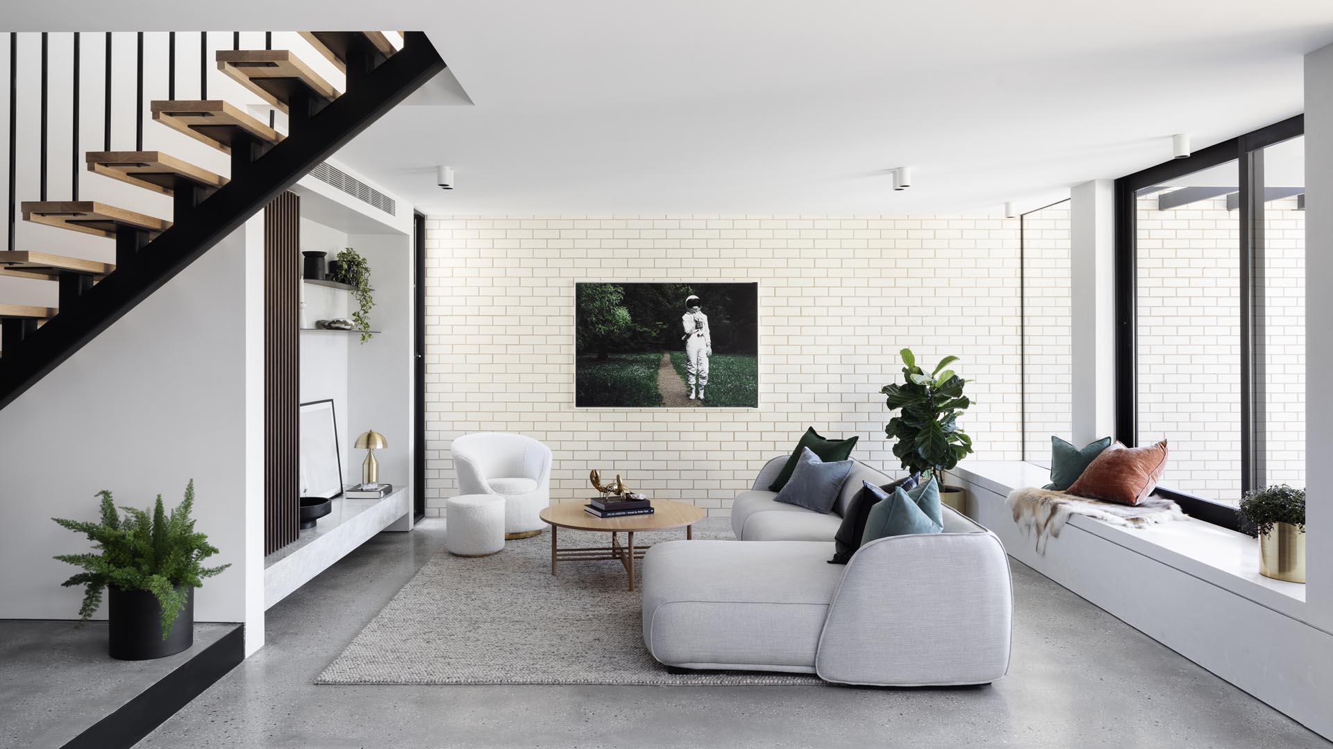 A modern white living room with a brick accent wall and built-in window bench.