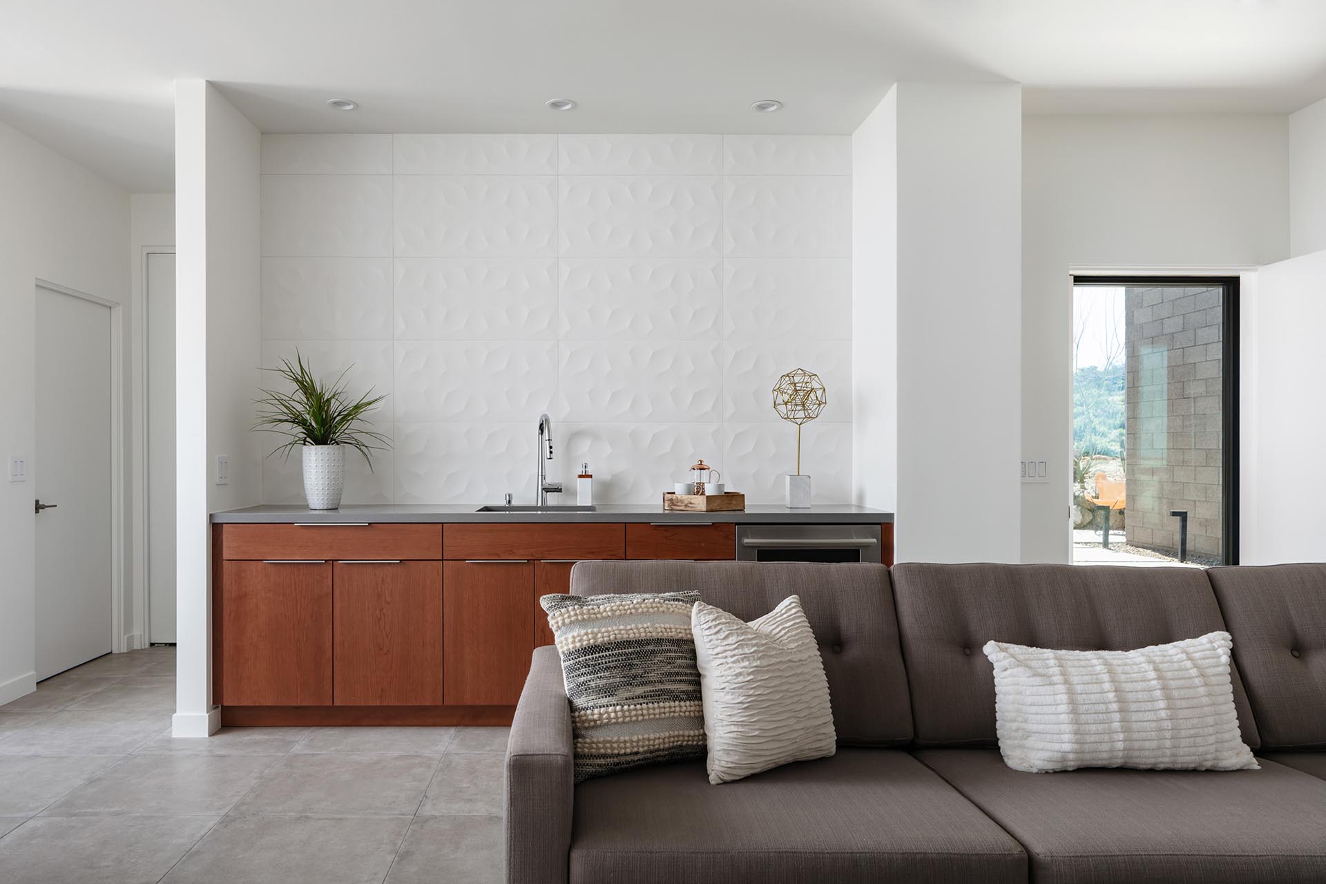 A small kitchenette with a 3d tile back splash runs from counter to ceiling.