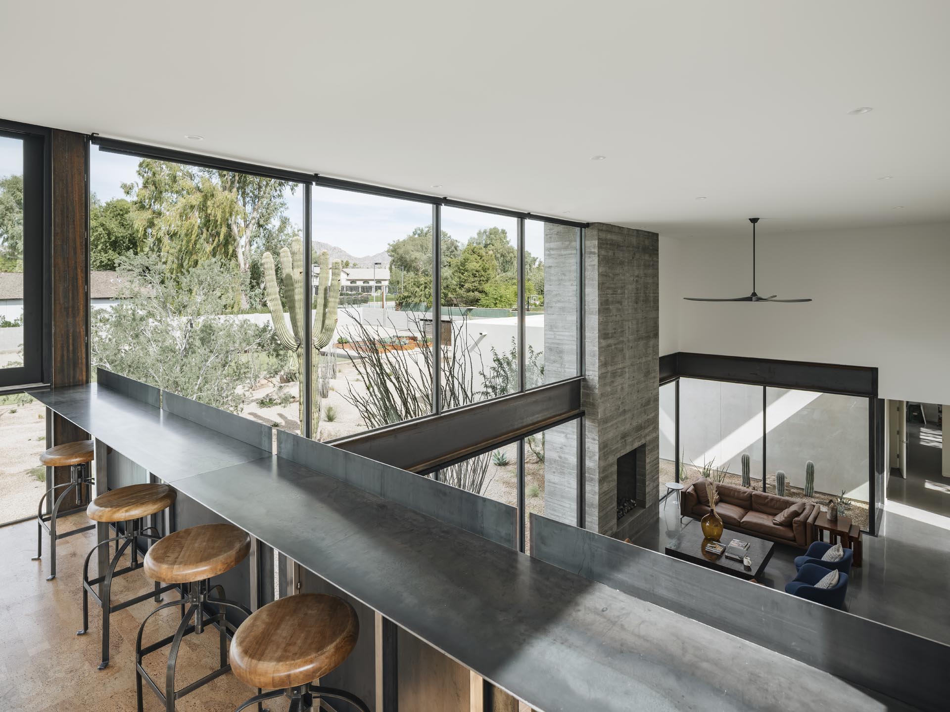 A lofted area has a steel bar for taking in the views of the lower level and distant mountain views.