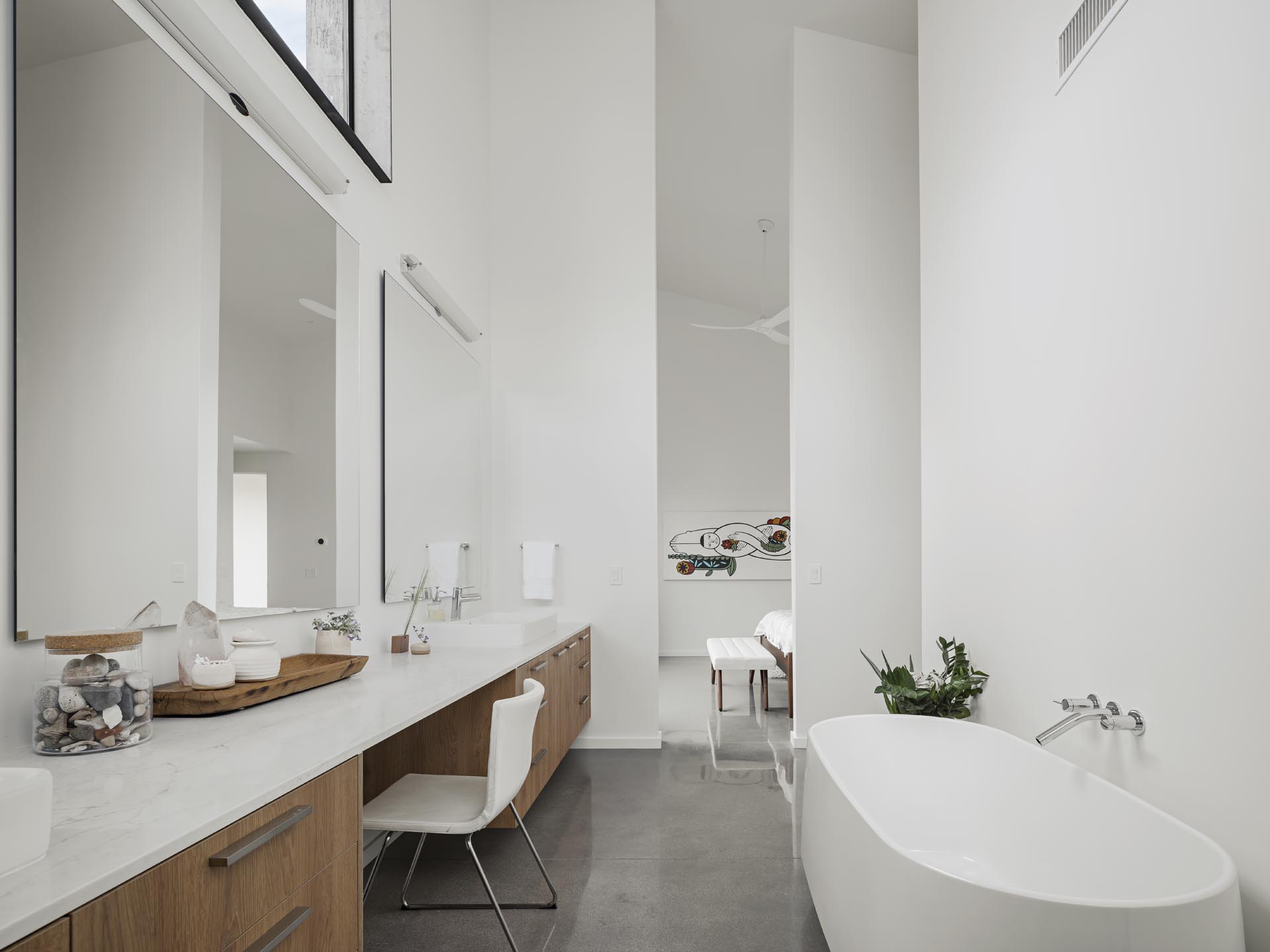 A modern en-suite bathroom has a long vanity as well as a freestanding bathtub.