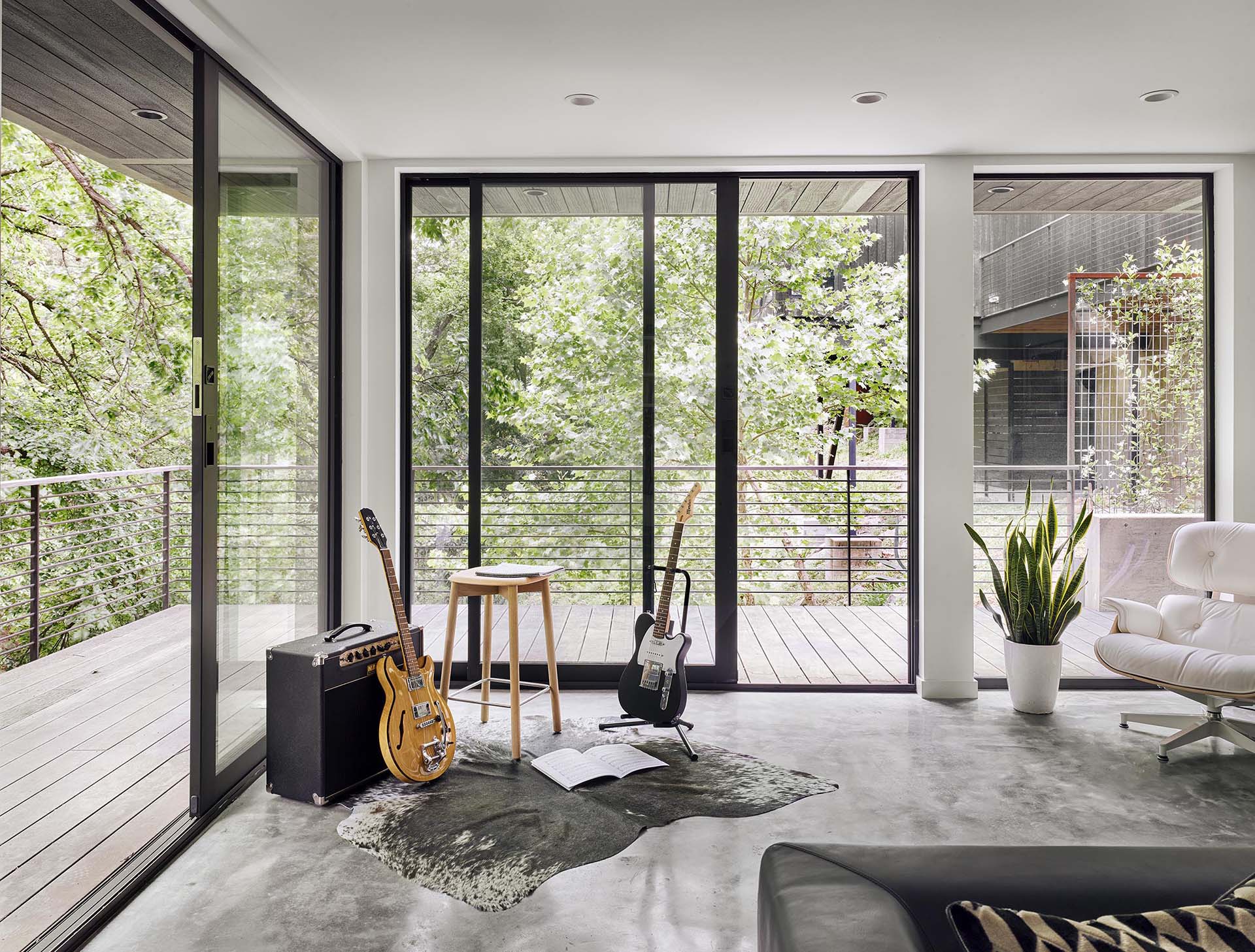 A modern living room with floor-to-ceiling windows and sliding glass doors.