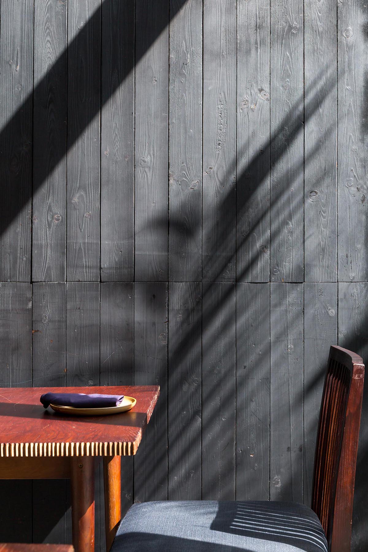 A contemporary restaurant with stained black wood walls.