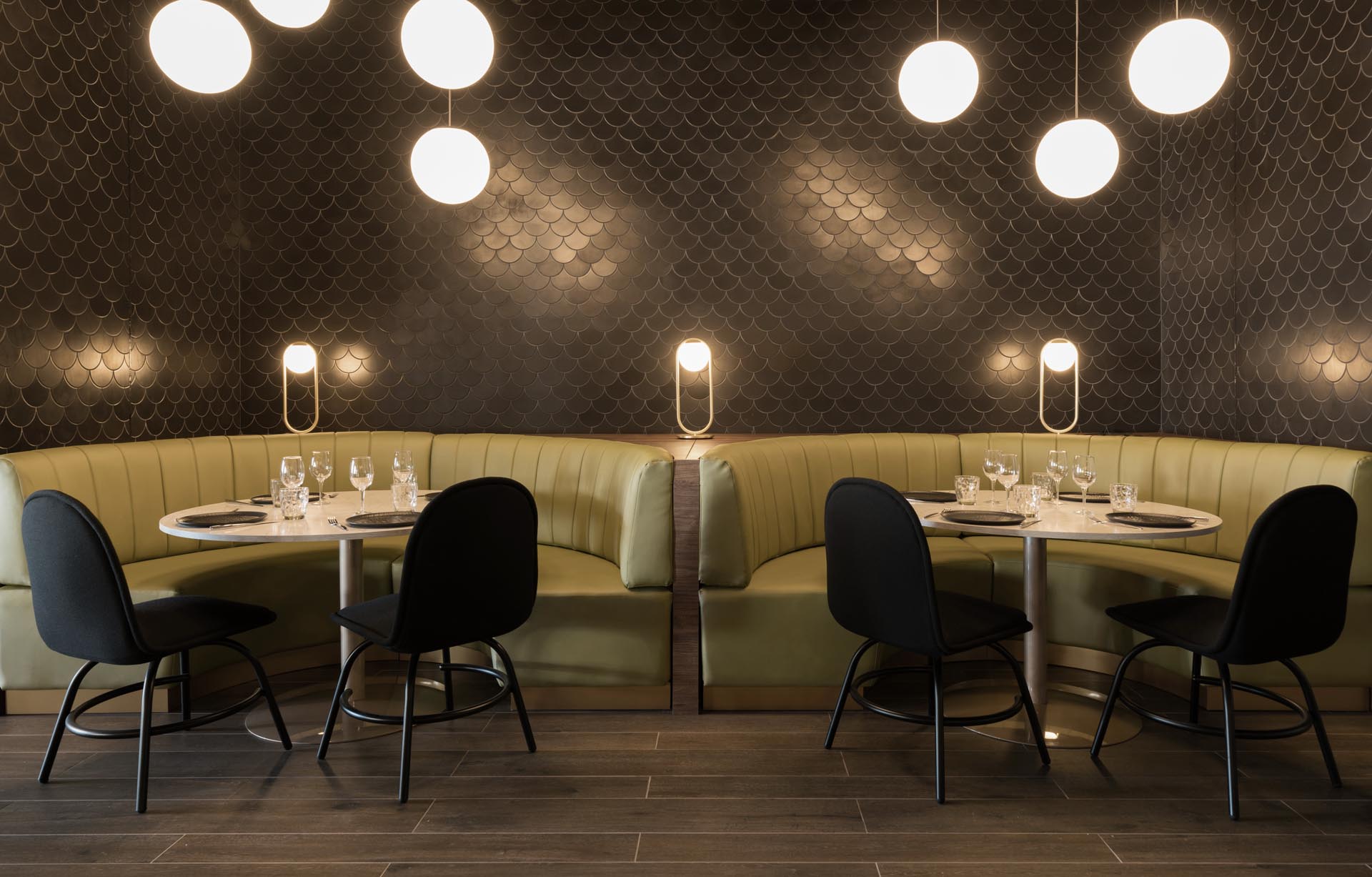 A modern restaurant with curved banquette booths, and black tiles designed to look like dragon scales.