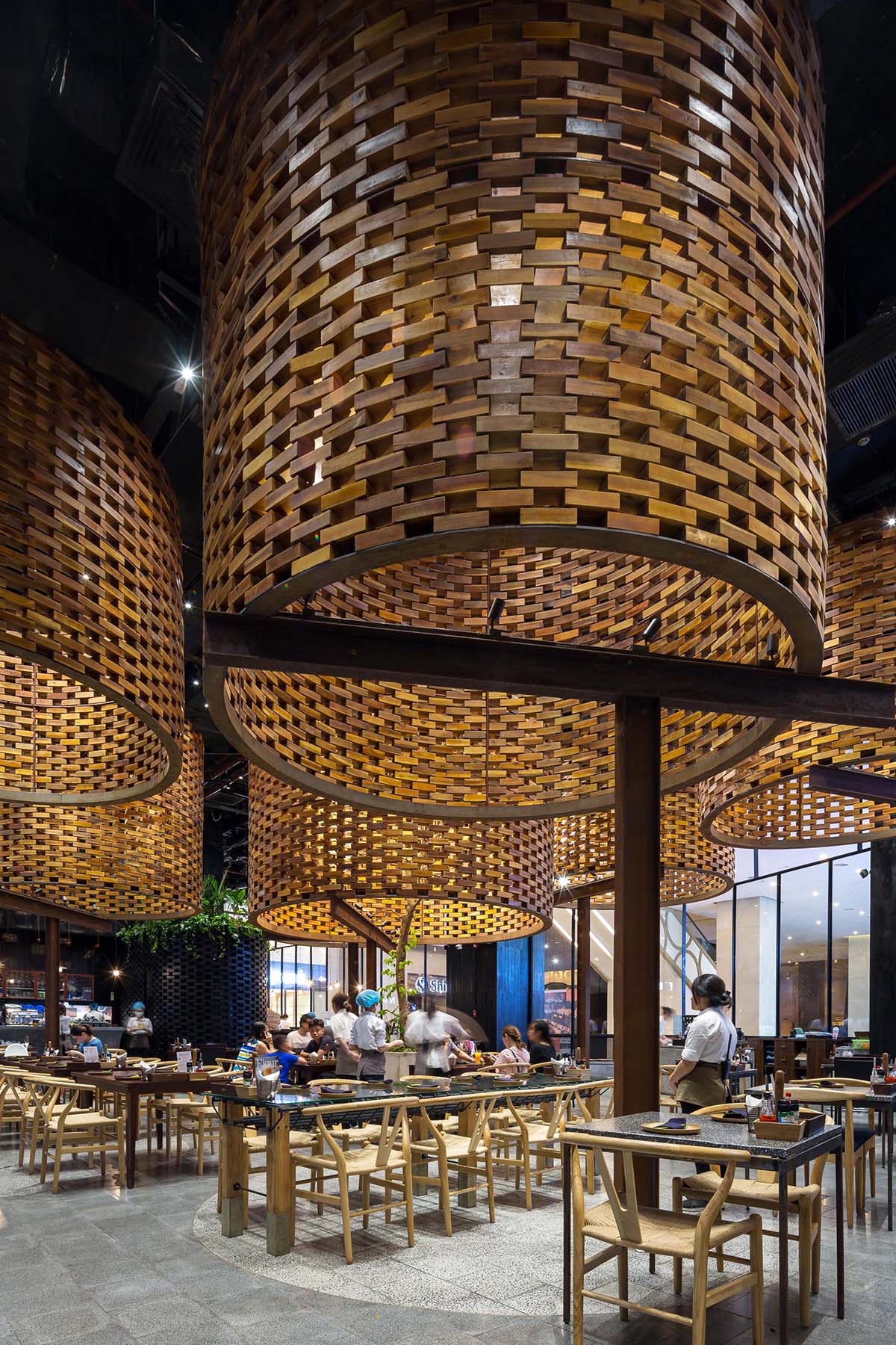 A modern restaurant with large sculptural cylinders made from wood bricks.