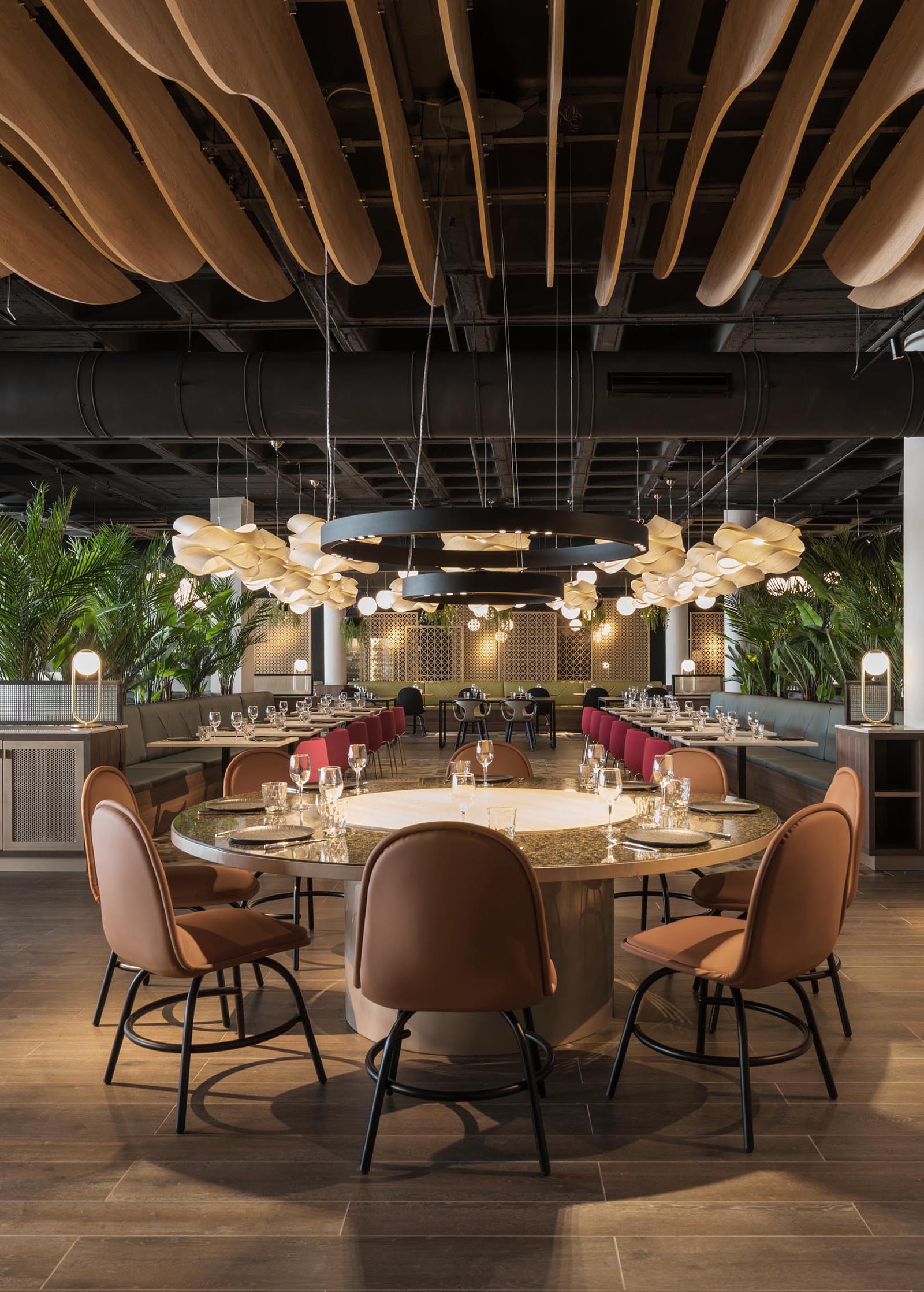 A modern restaurant with sculptural wood elements, a crown of lights, and multiple seating areas.