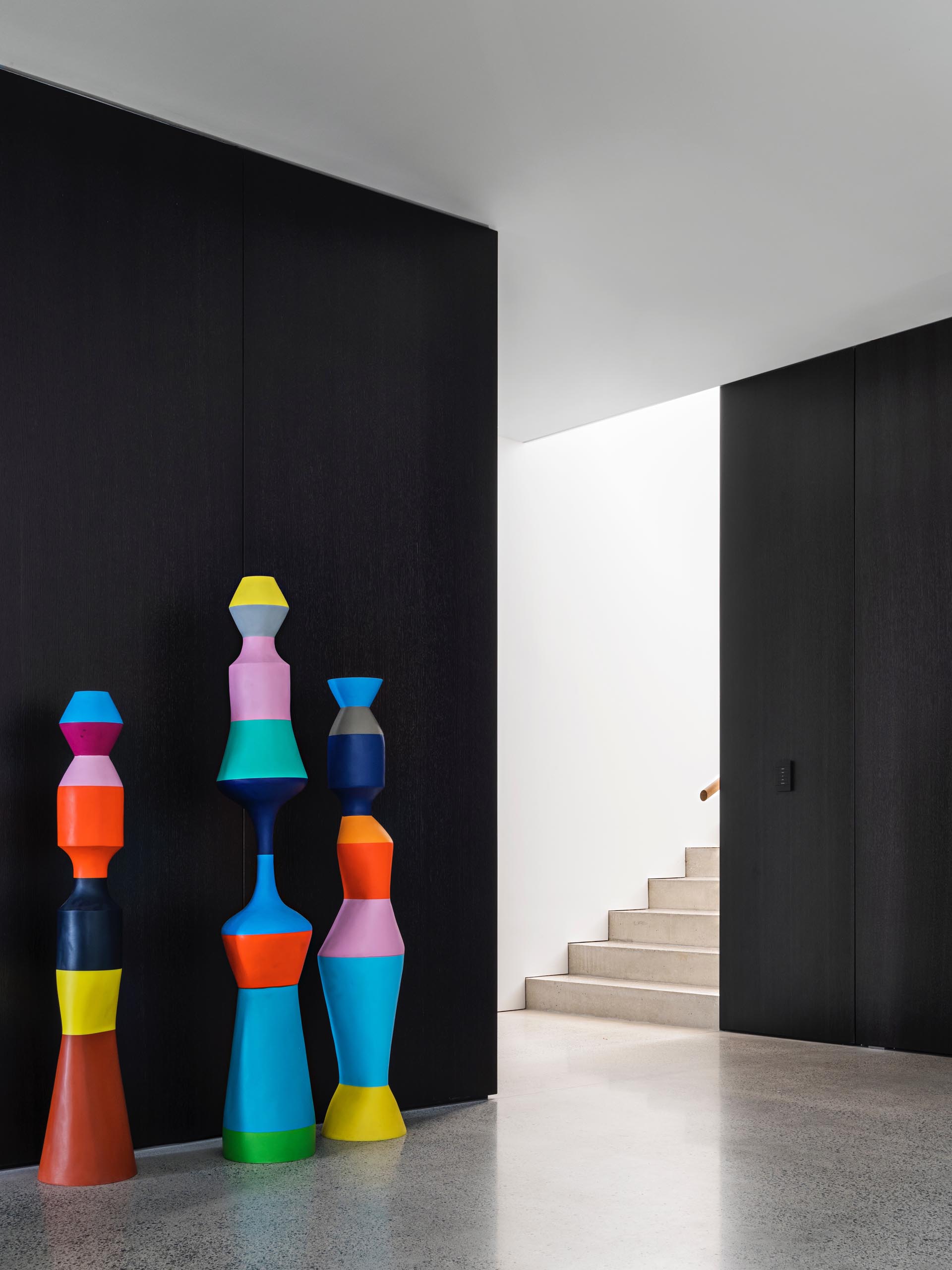 A modern interior with colorful sculptures against a black wall.