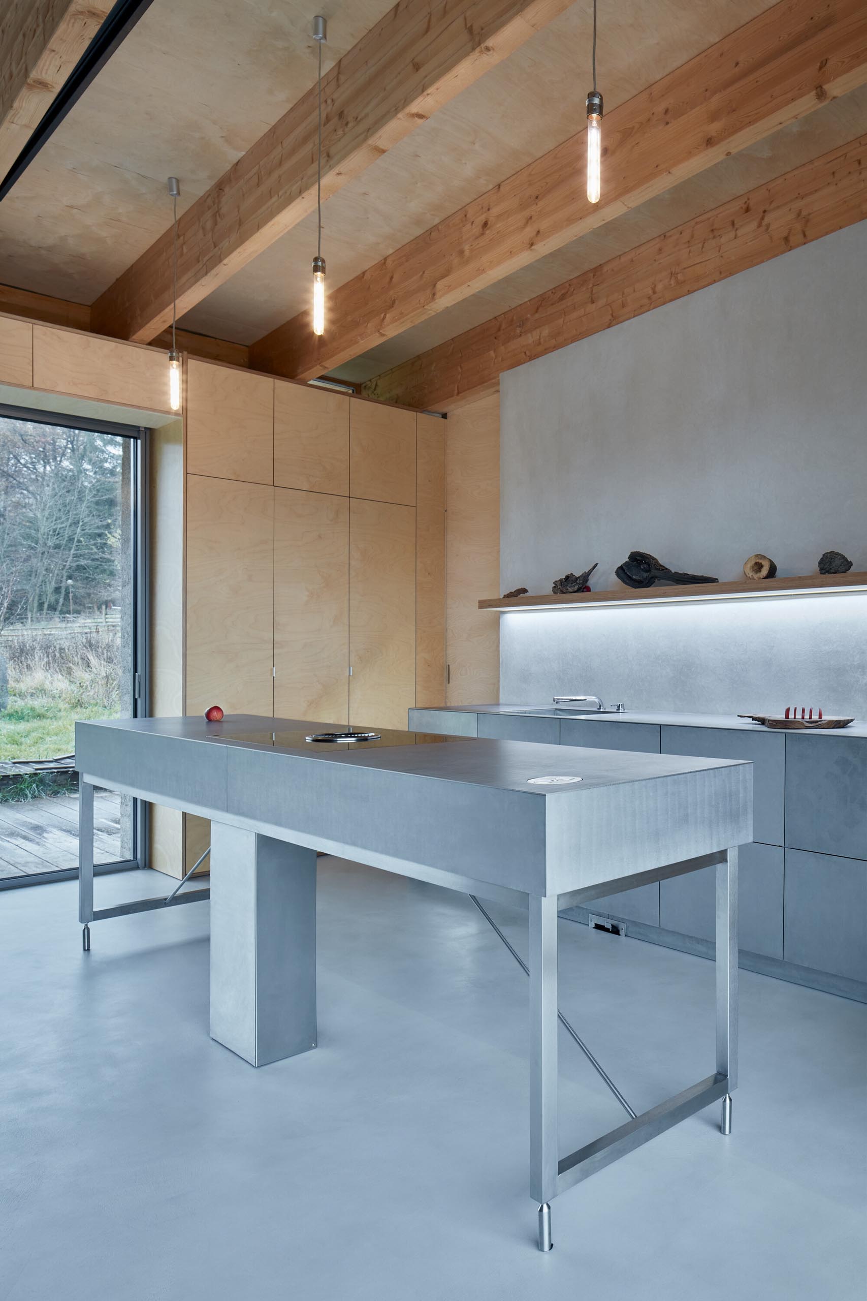 A modern cabin with a stainless steel kitchen and plywood walls.