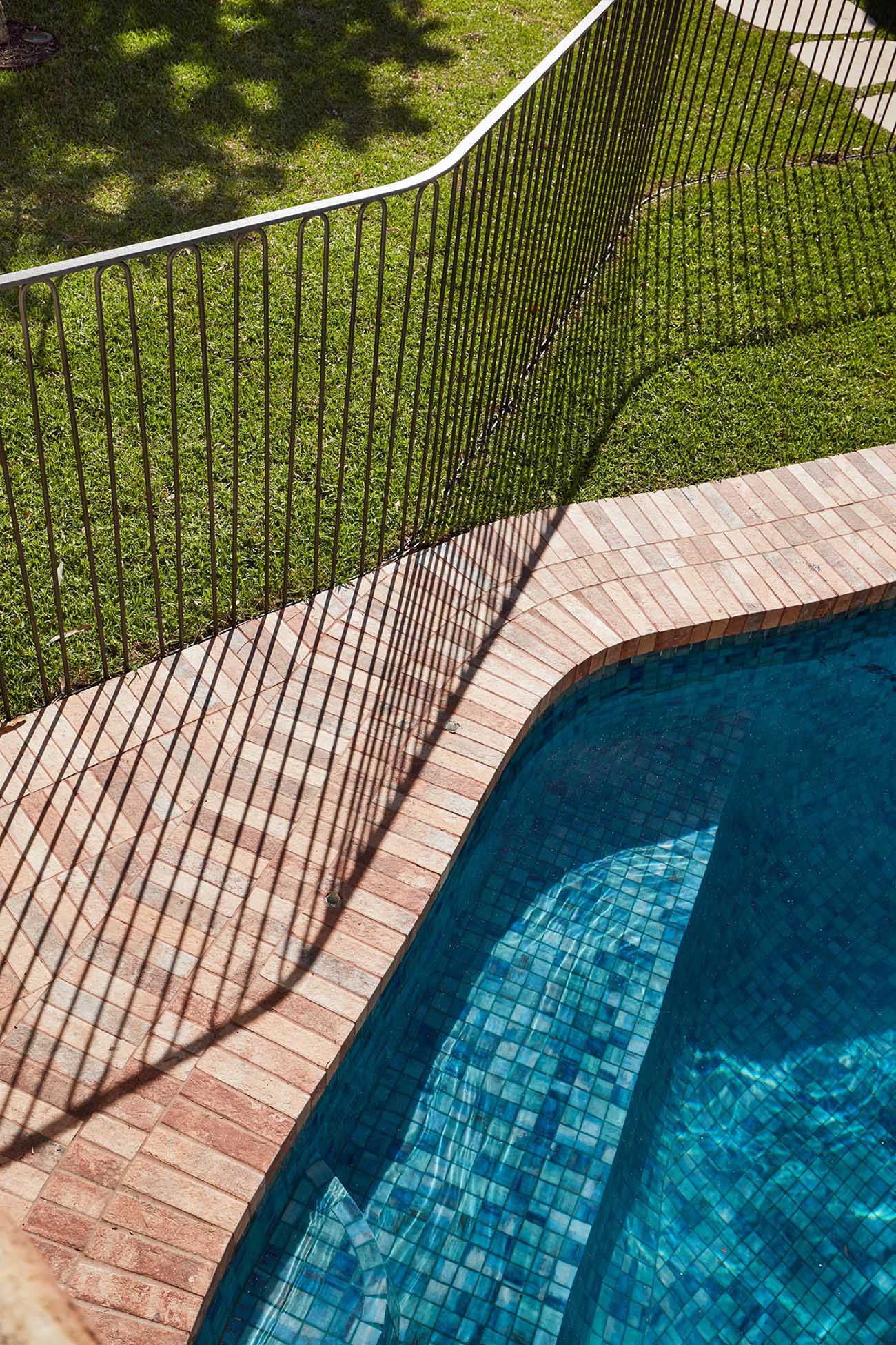 A modern safety fence surrounds a swimming pool.