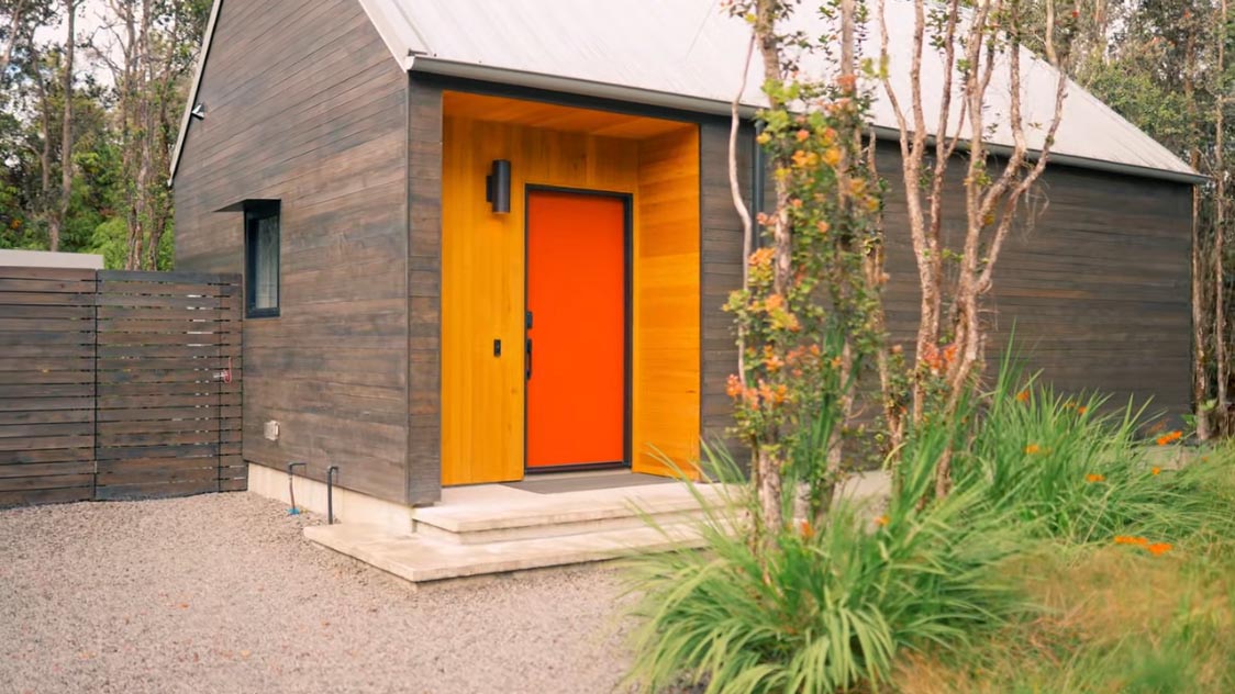 A modern tiny home with a bright orange door.