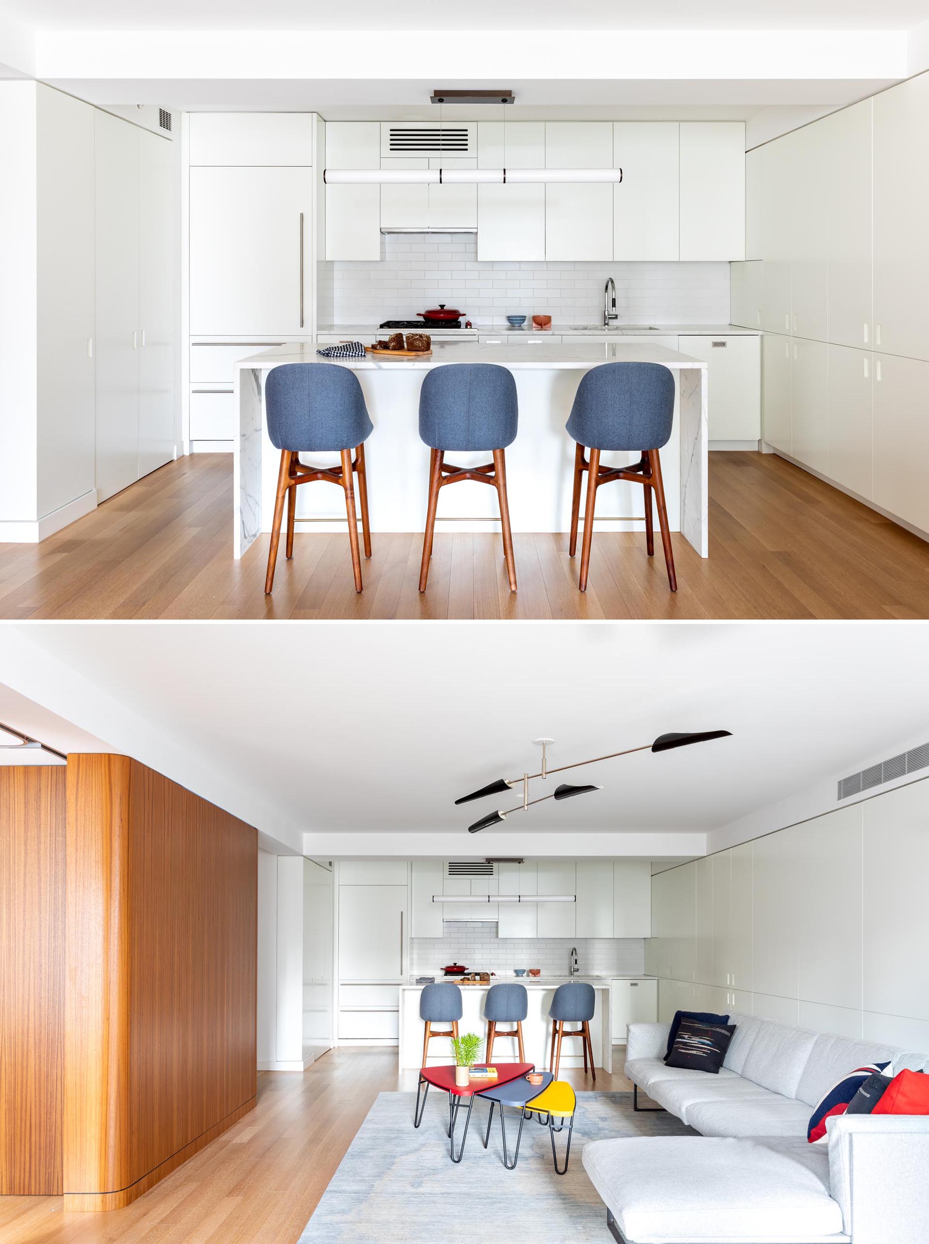 A modern kitchen has been kept bright with modern white cabinets, integrated appliances, subway tiles, and a matching island. 