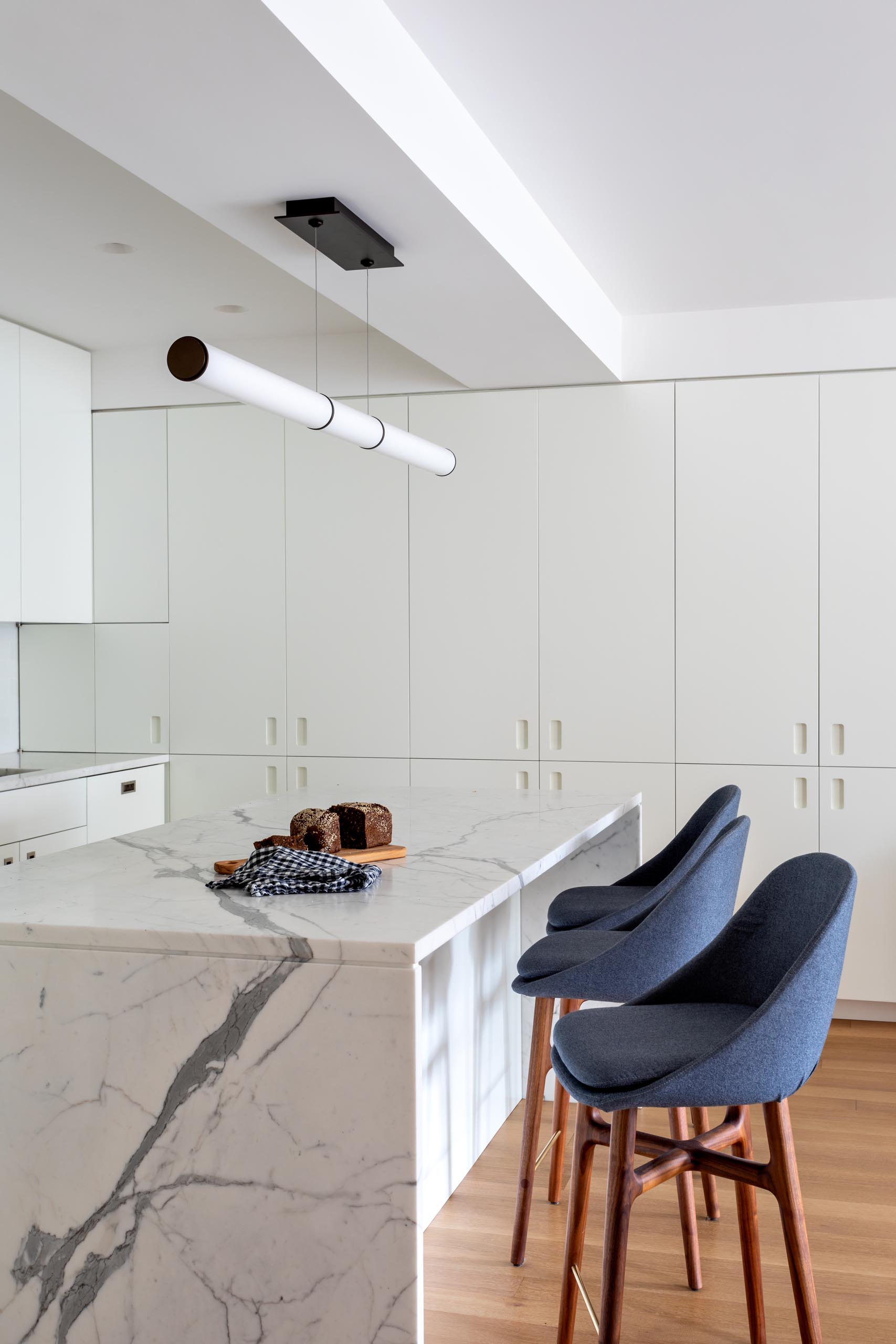 A modern kitchen has been kept bright with modern white cabinets, integrated appliances, subway tiles, and a matching island.