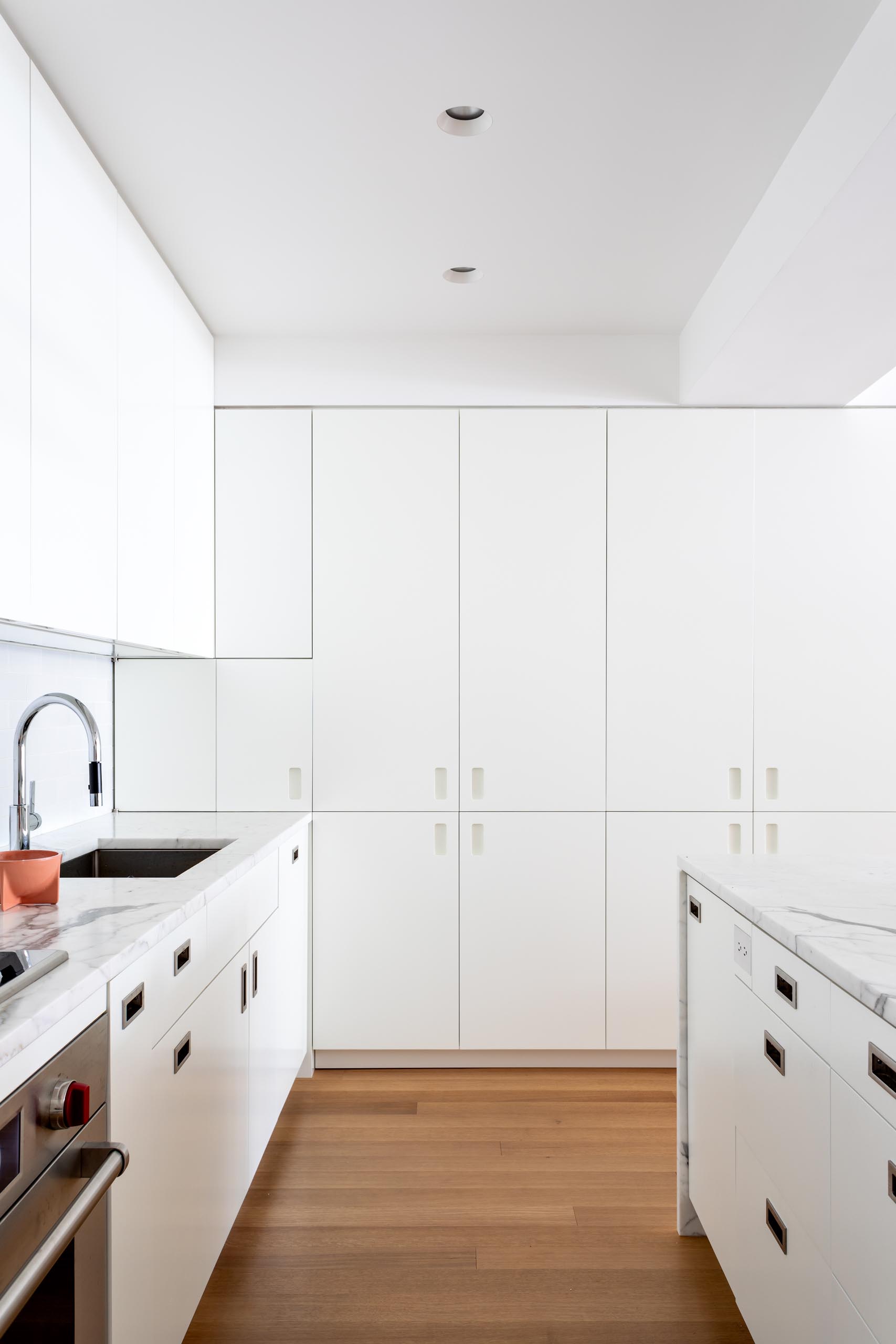 A modern kitchen has been kept bright with modern white cabinets, integrated appliances, subway tiles, and a matching island. 