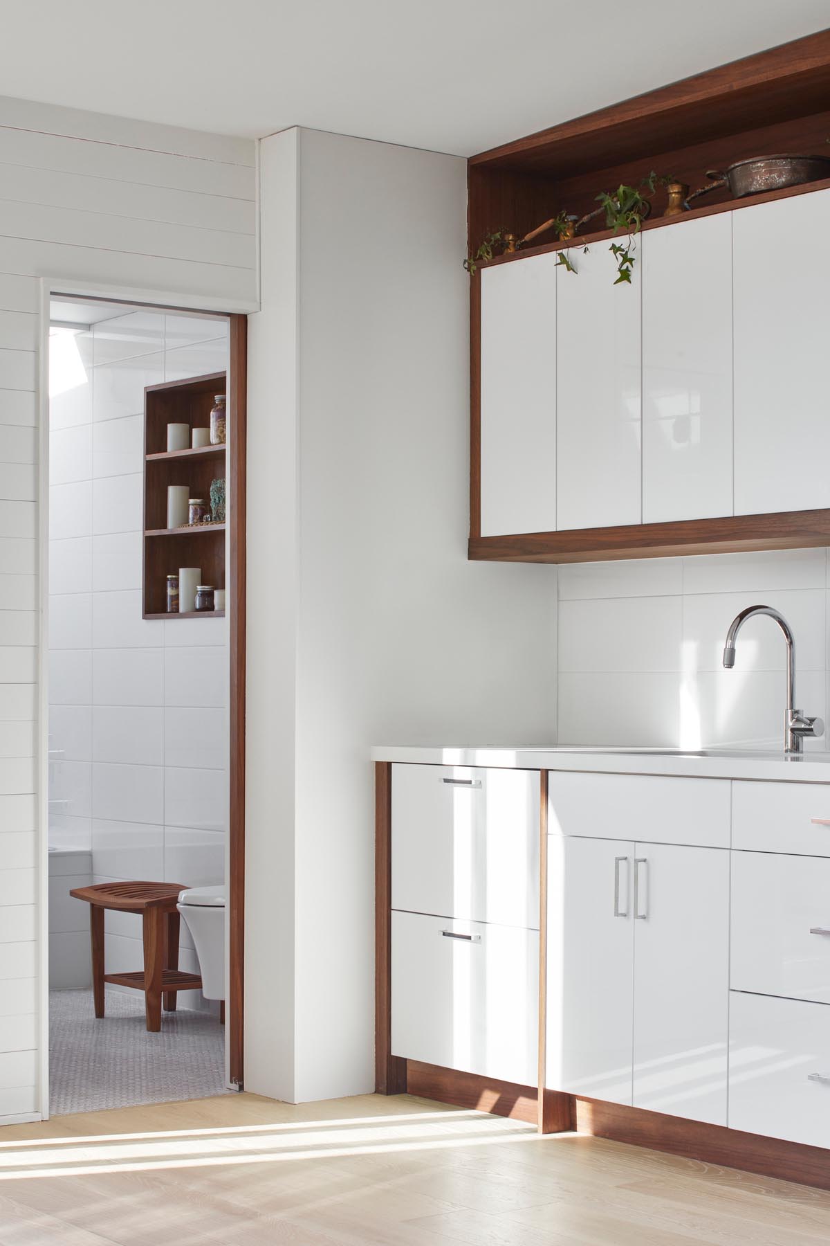 A small kitchenette with white and wood cabinetry and a matching white countertop.