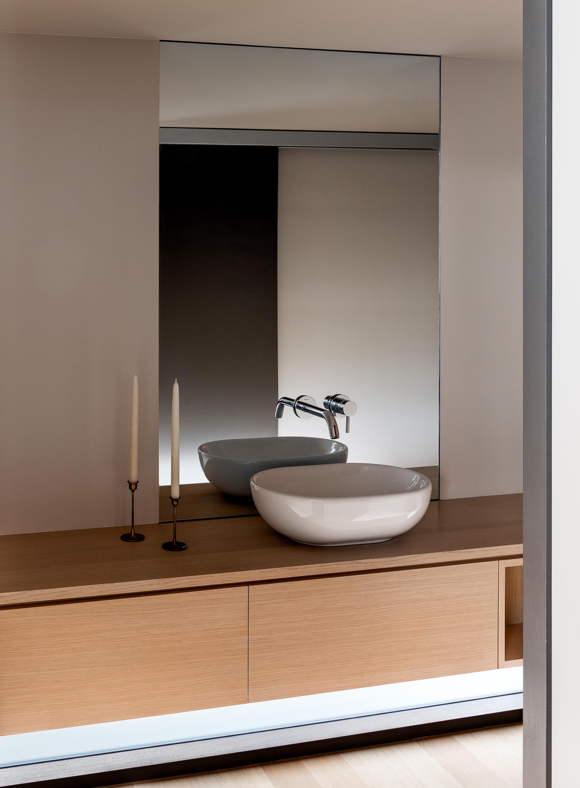 In this modern bathroom, there's a floating wood vanity with hidden lighting tucked away in the corner.