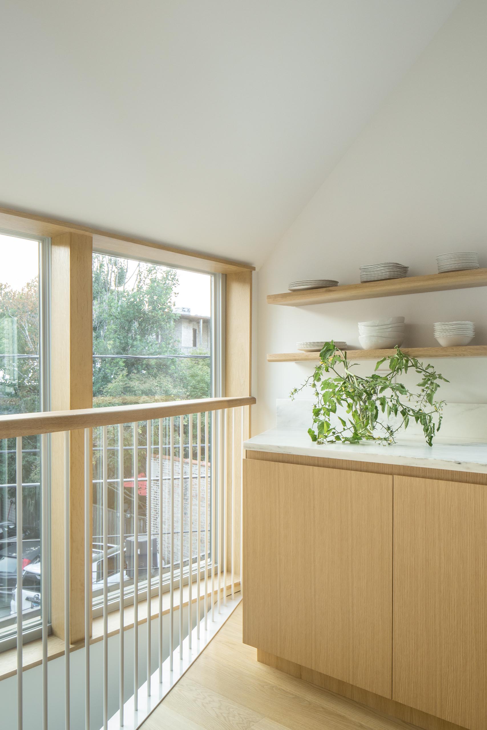 This modern kitchen has floating wood shelves, white countertops, and an island with seating. 