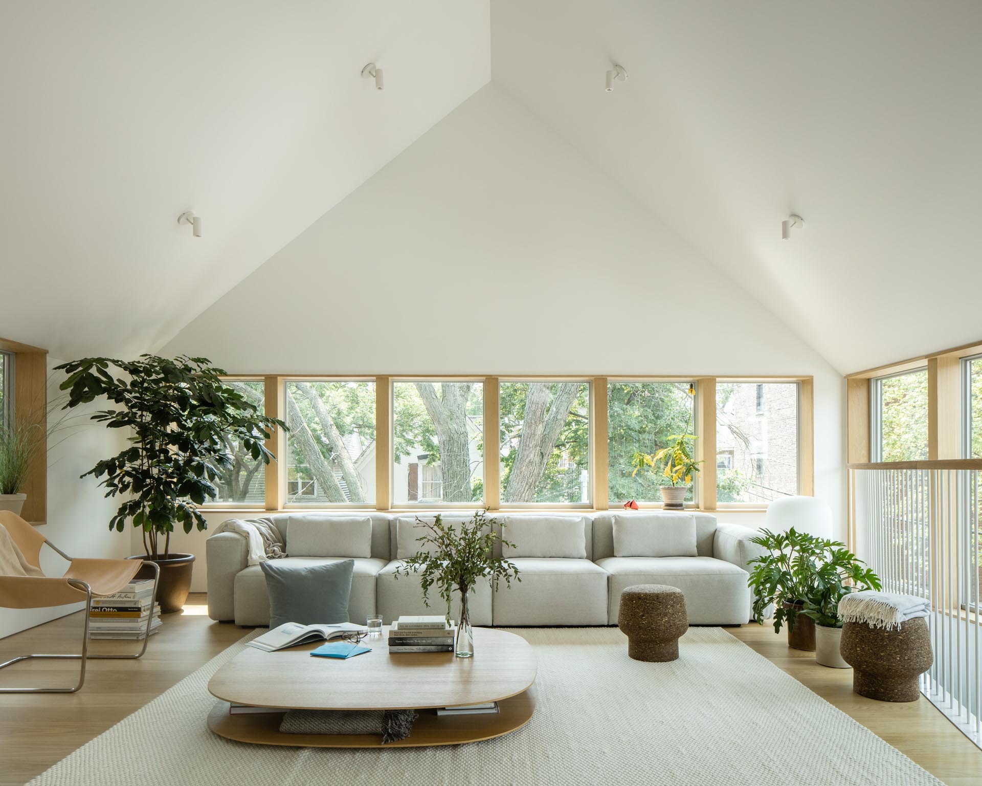 This modern living room has a vaulted ceiling, wood window frames, and minimalist furnishings.