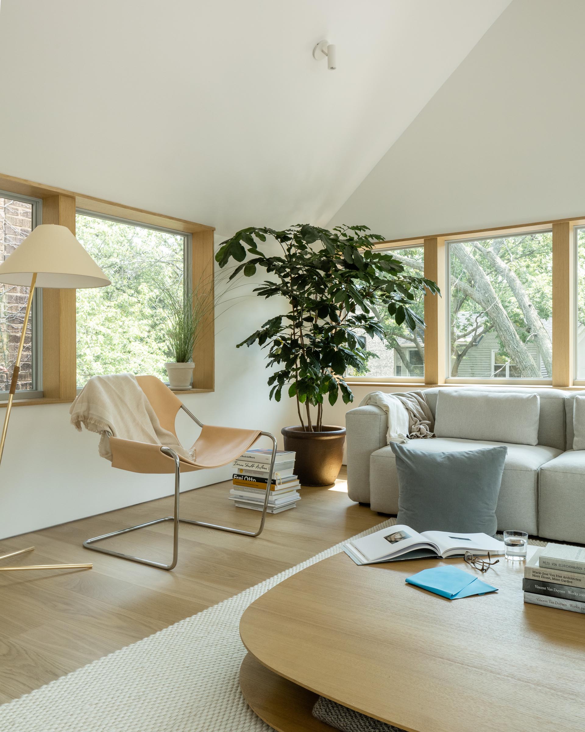 This modern living room has a vaulted ceiling, wood window frames, and minimalist furnishings.