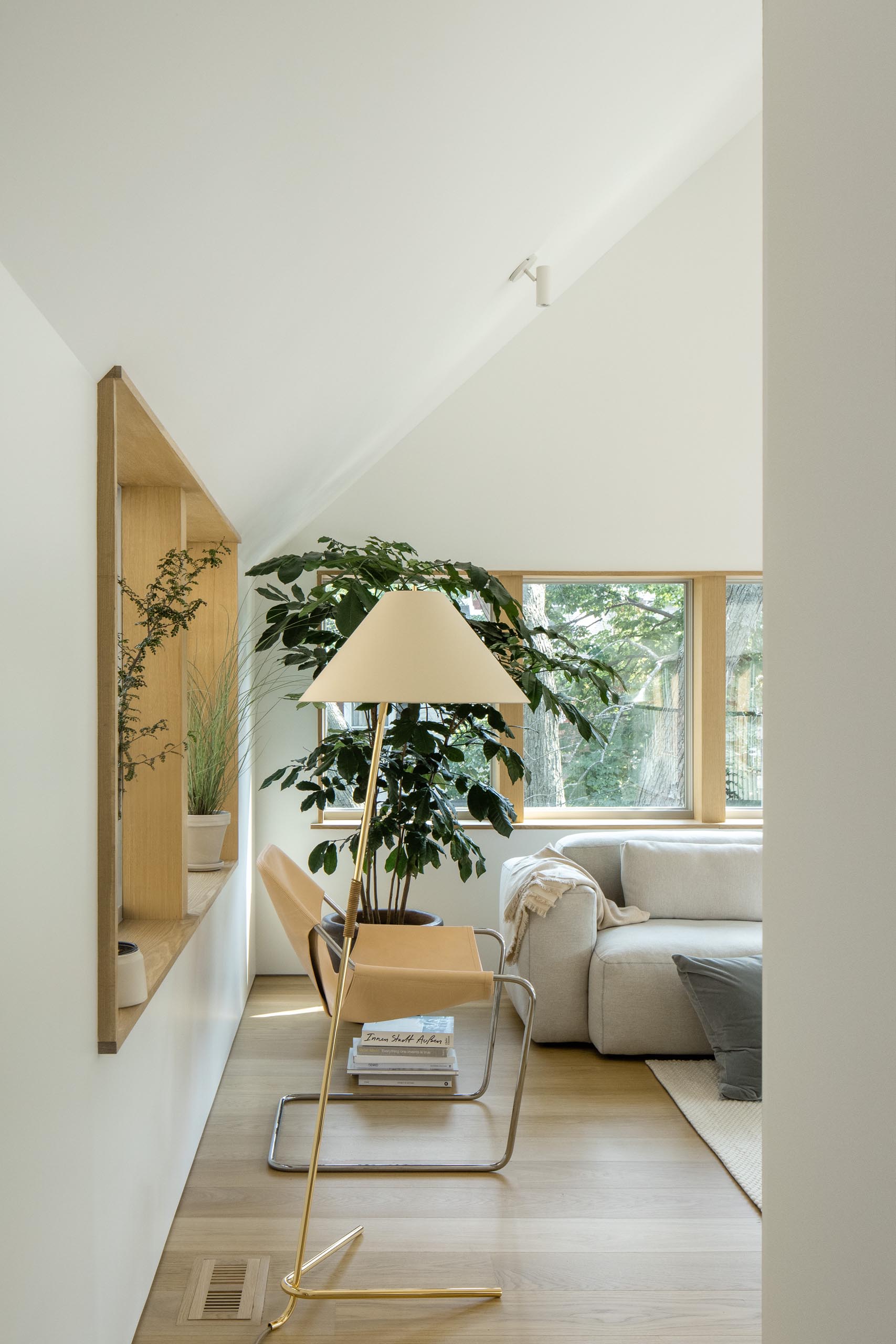 This modern living room has a vaulted ceiling, wood window frames, and minimalist furnishings.