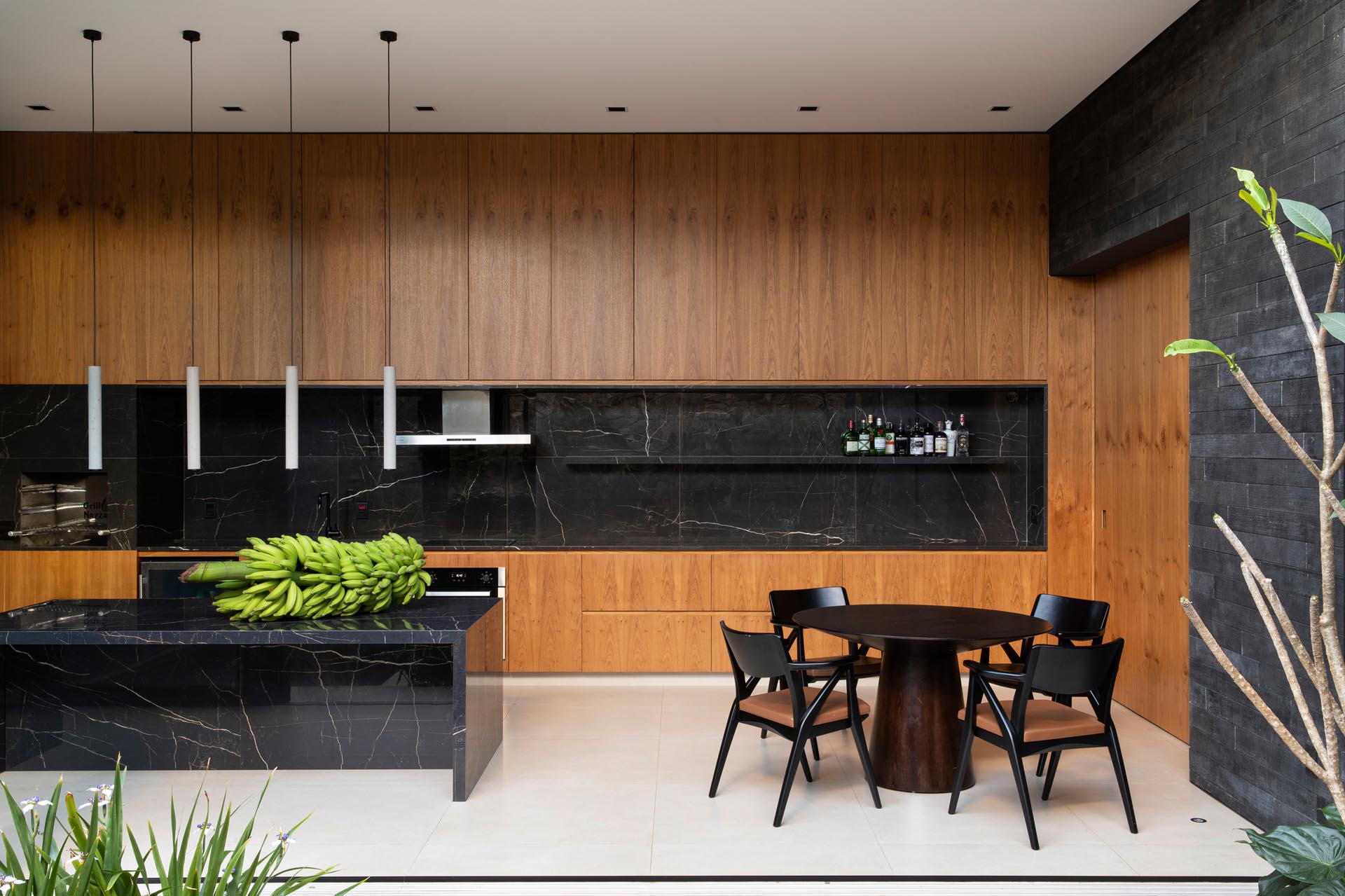 In this modern kitchen, the wood cabinets are contrasted by black stone that used for the backsplash, floating shelf, and island.