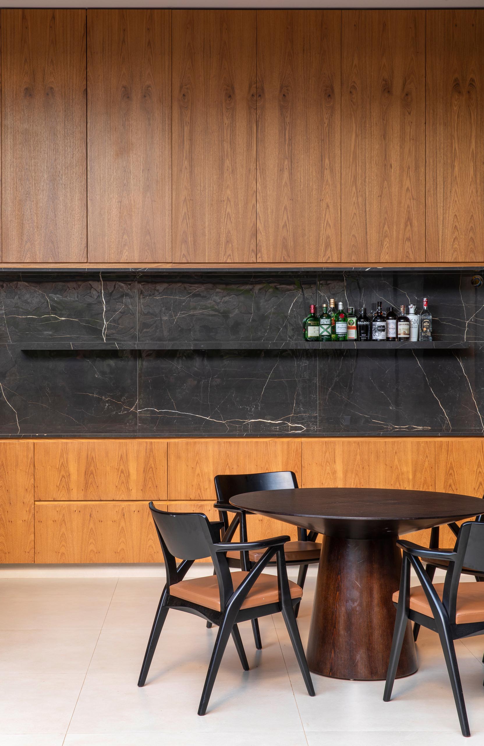 In this modern kitchen, the wood cabinets are contrasted by black stone that used for the backsplash, floating shelf, and island.