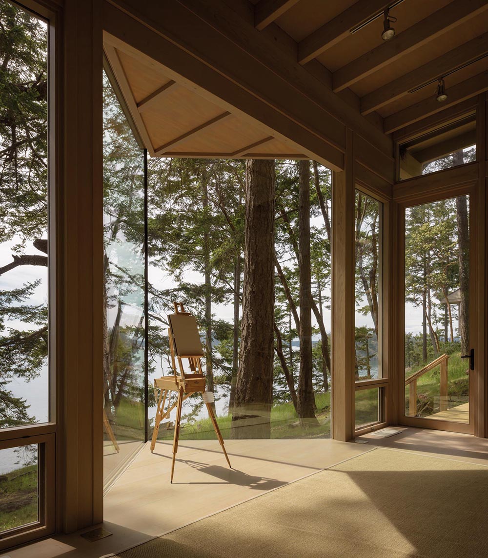 A small wood cabin that's designed as an artist cabin or guest house, and has glass walls.