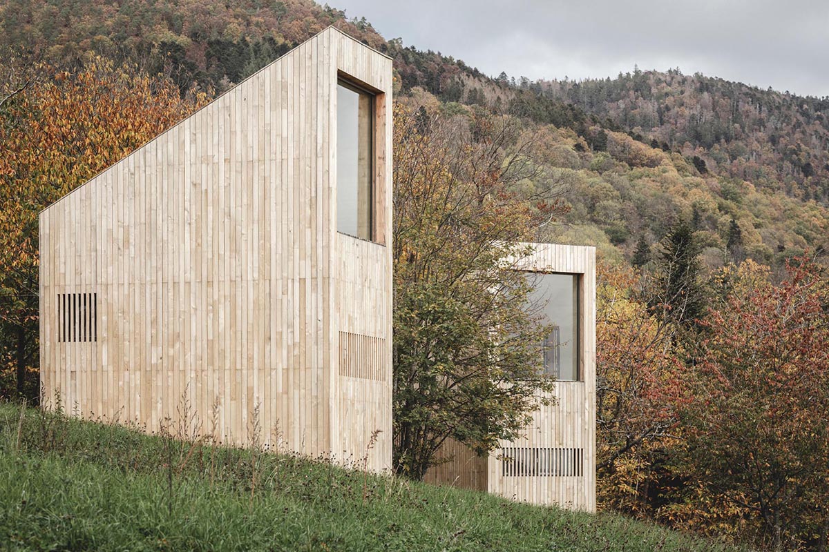 Modern cabins with a vertical design, light wood exterior, and large windows.