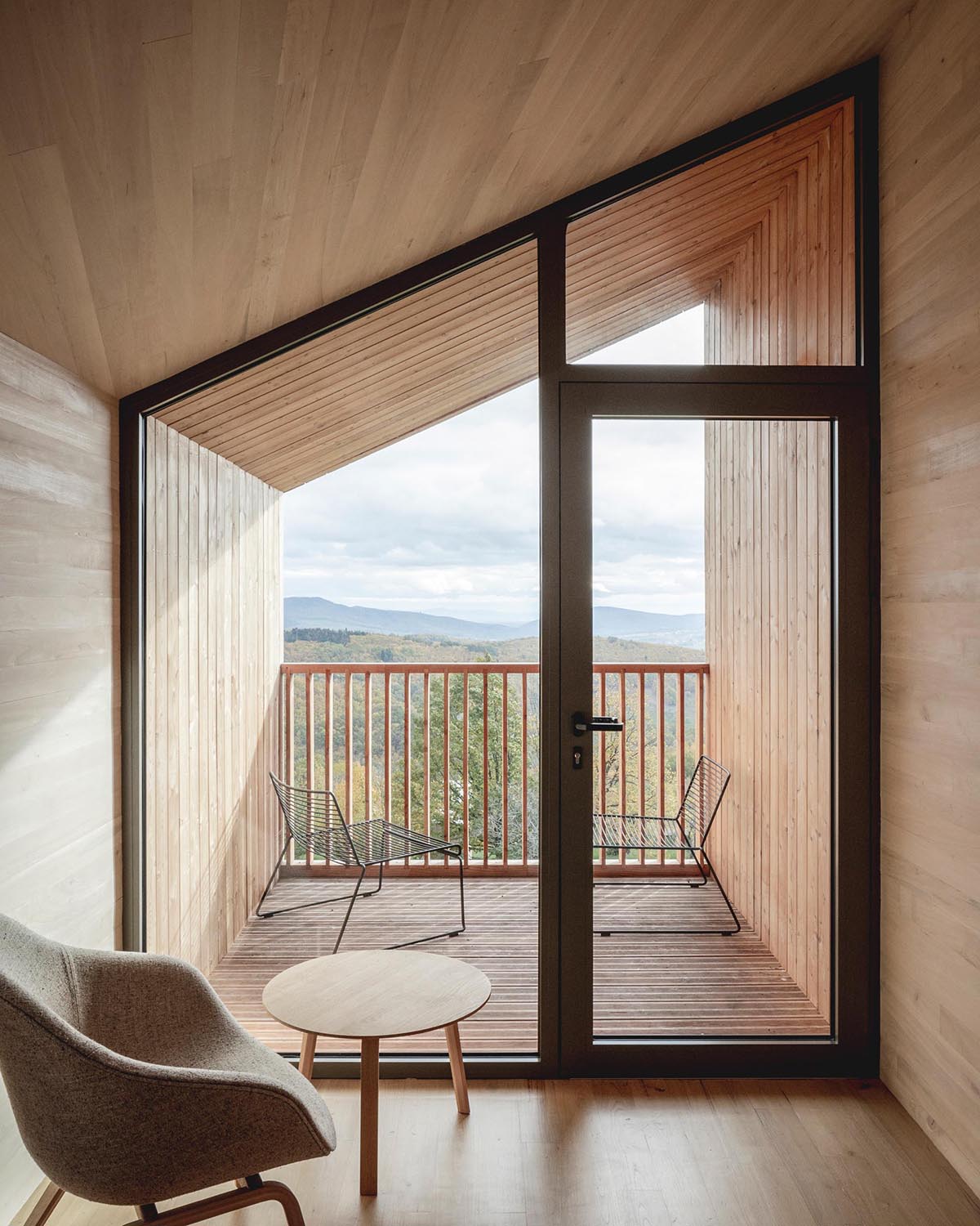 A modern cabin with a wall of glass that opens to a small covered balcony.