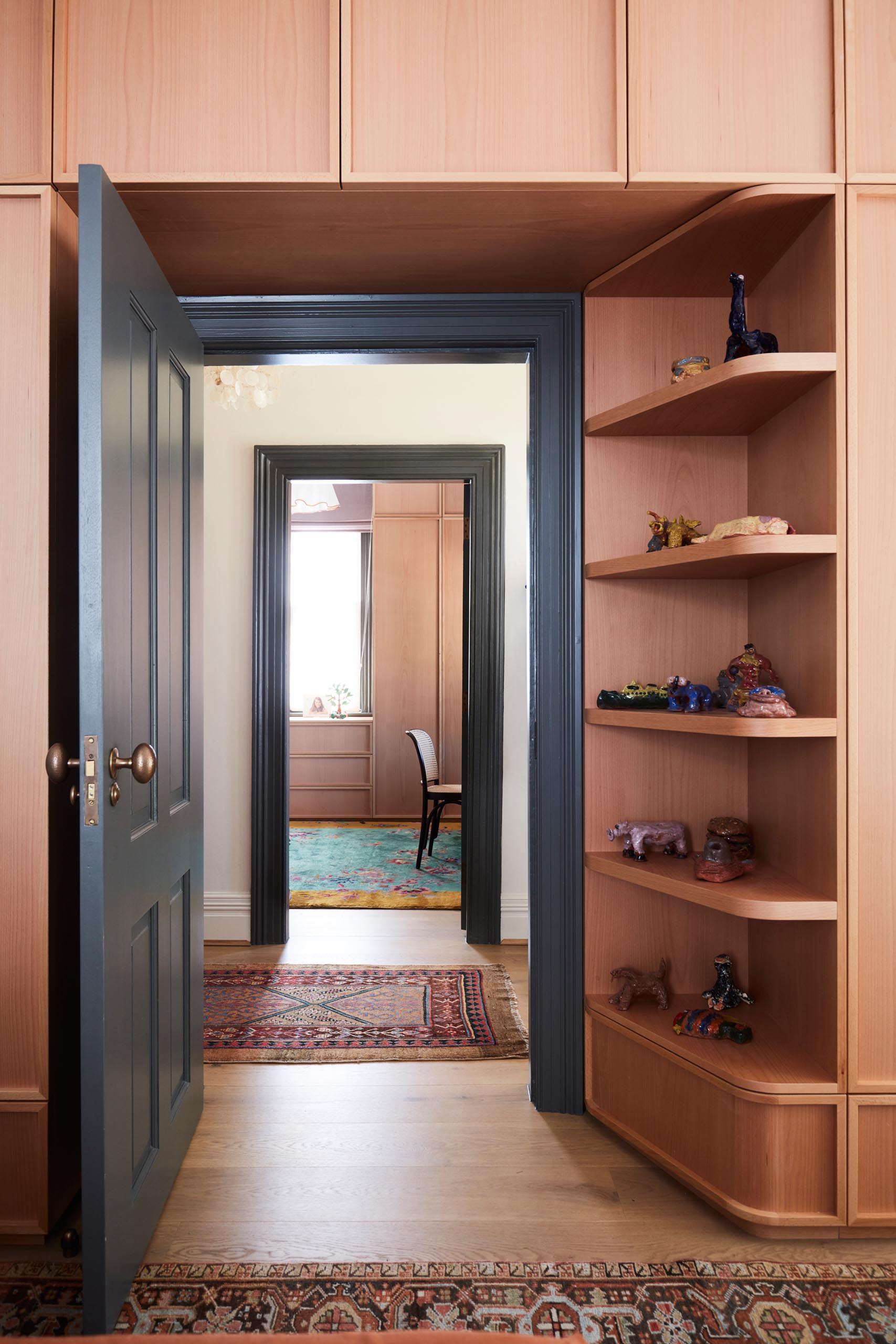 Custom-designed wood storage cabinets with open shelving that wrap around the door.