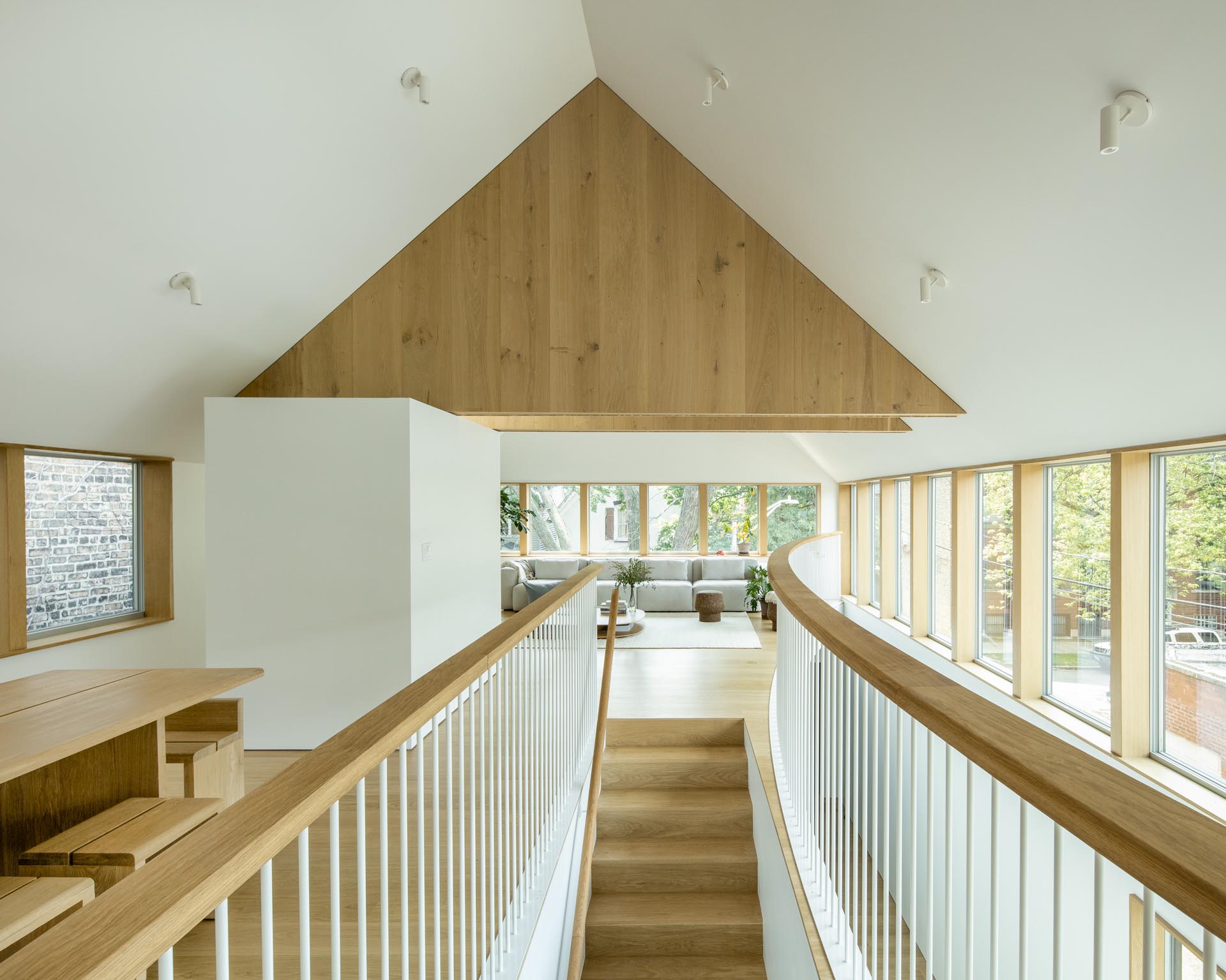 Wood stairs with a matching handrail and railing lead up to the social areas of this modern home.