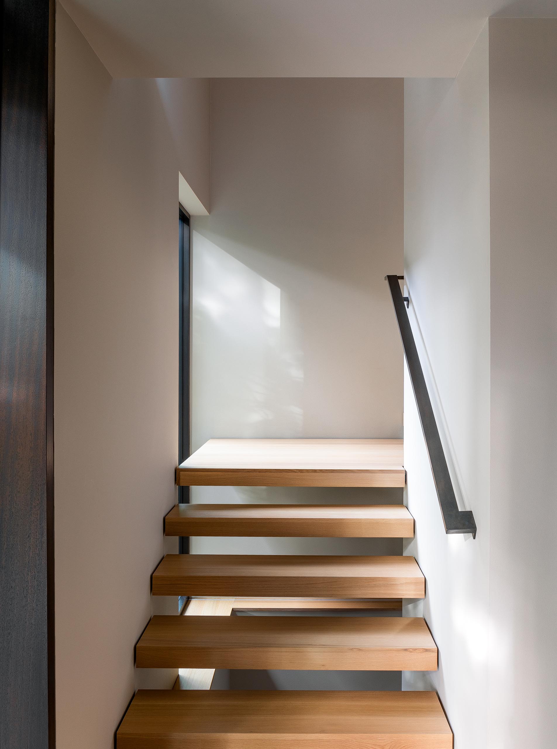 Wood stairs connect the upper social areas of this modern home with the bedrooms and bathrooms that are located on the lower level.