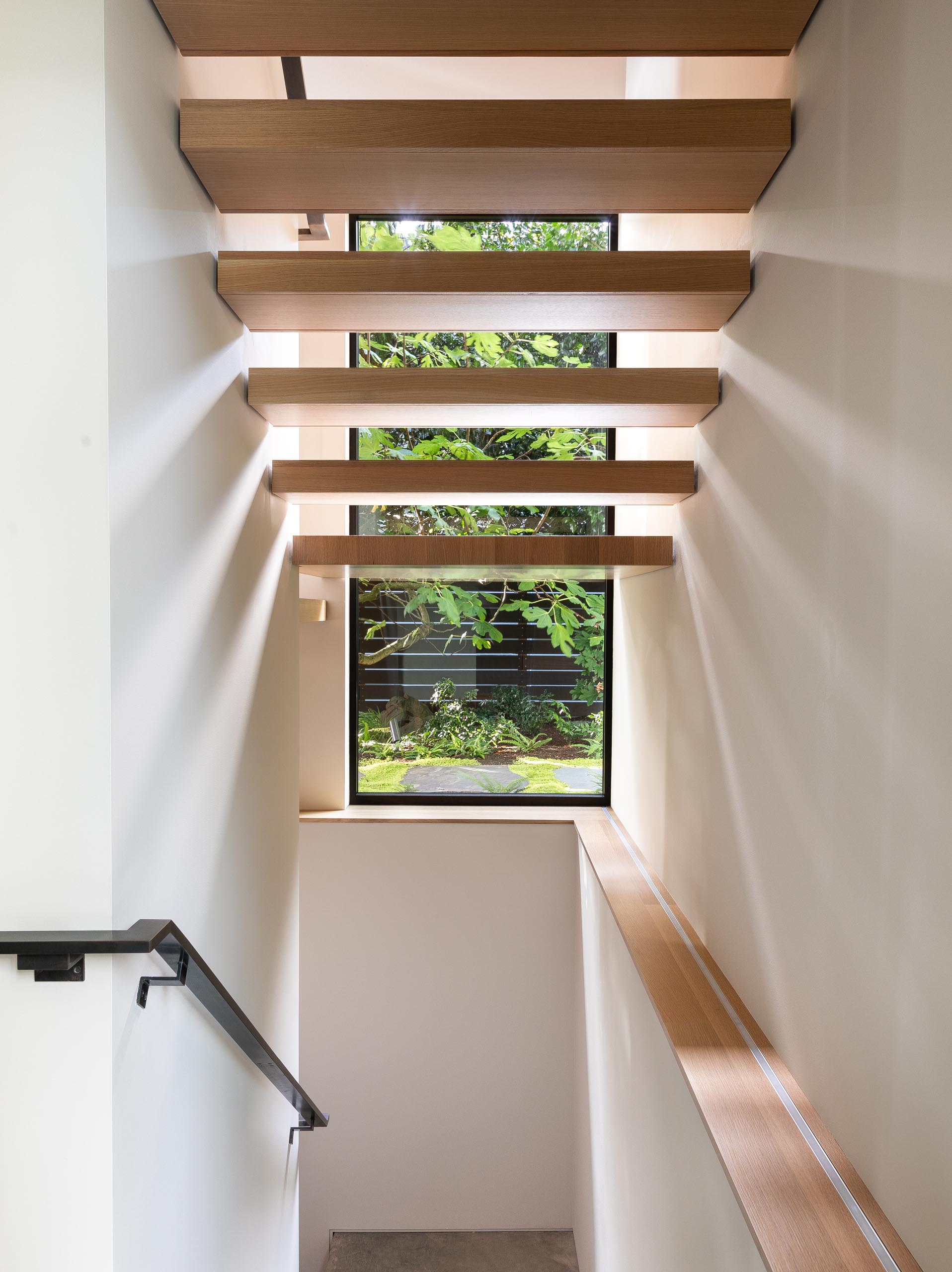 Wood stairs connect the upper social areas of this modern home with the bedrooms and bathrooms that are located on the lower level.