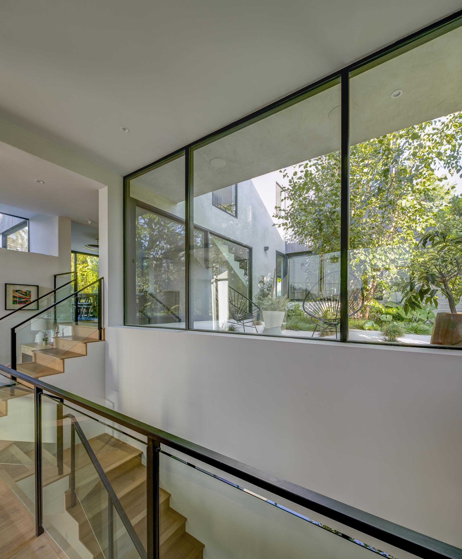 Connecting the various levels of this modern house are wood stairs that have a glass and metal railing.