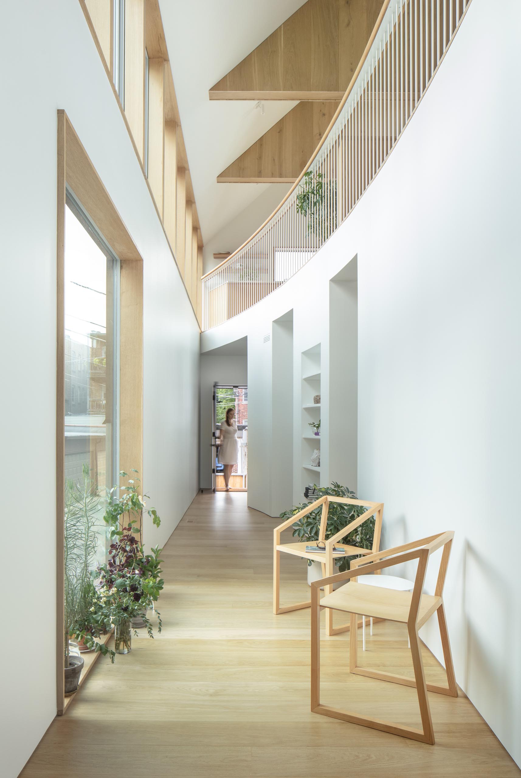 This modern home features a curved double-height atrium with seating, built-in closet, and a reading nook.