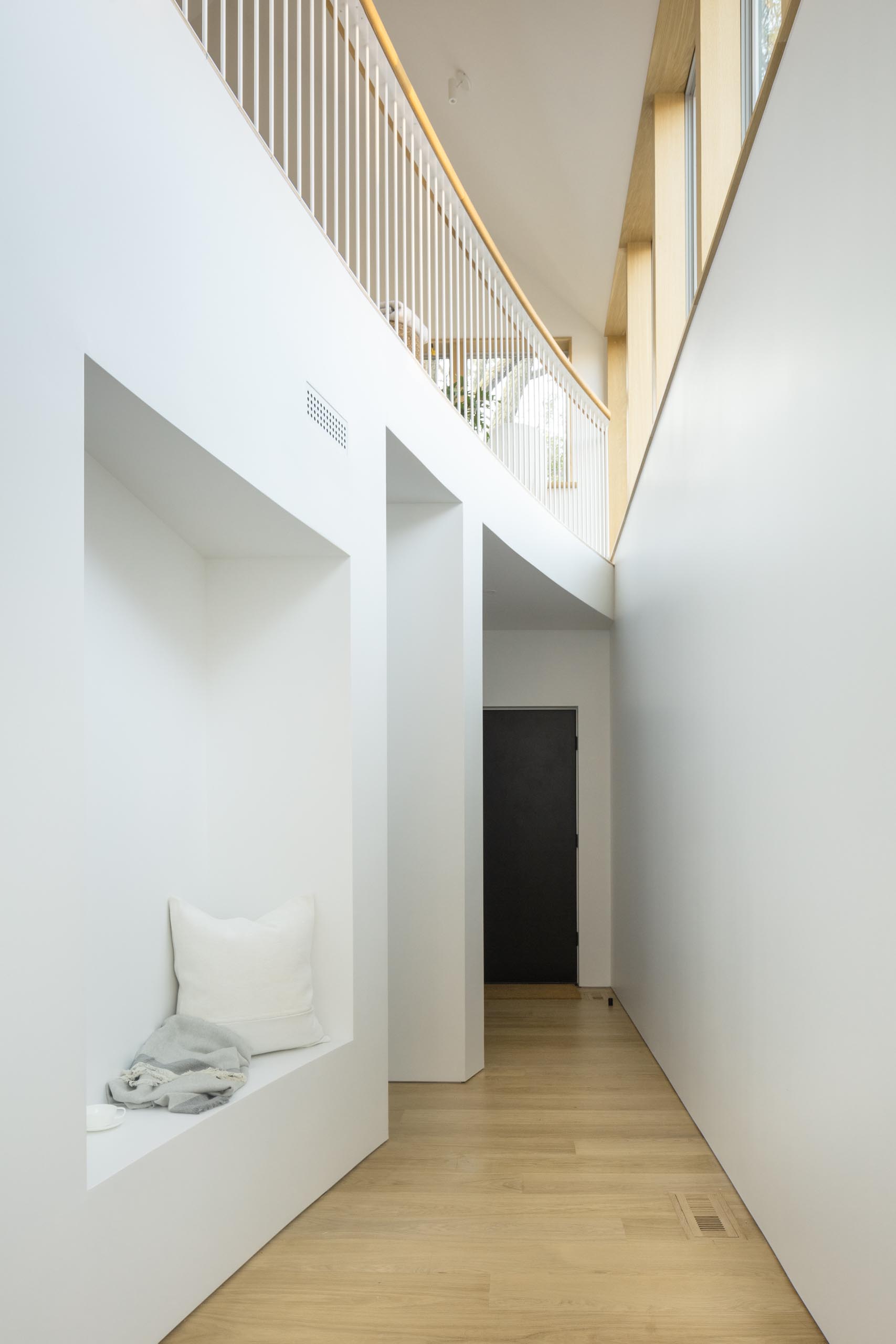 This modern home features a curved double-height atrium with seating, built-in closet, and a reading nook.