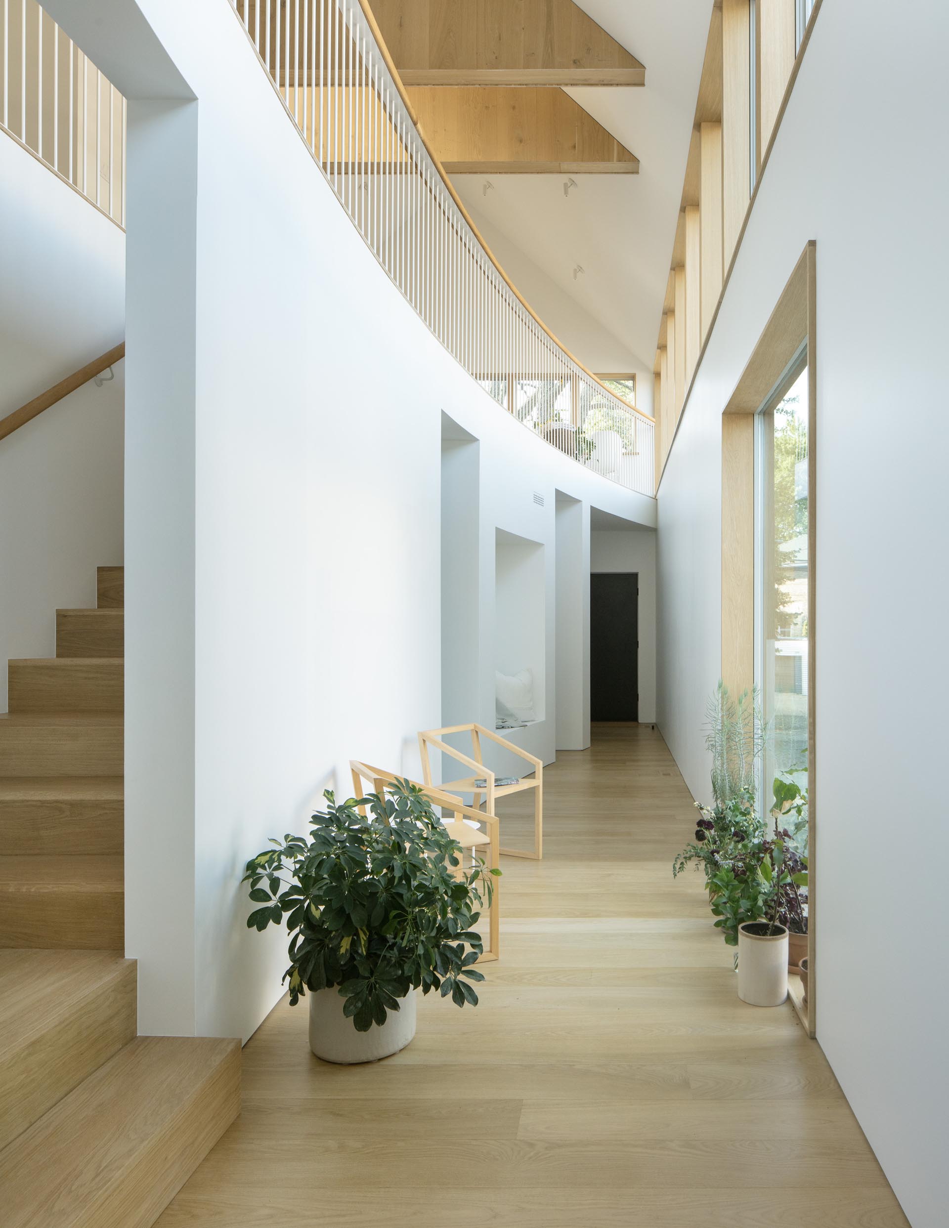 This modern home features a curved double-height atrium with seating, built-in closet, and a reading nook.